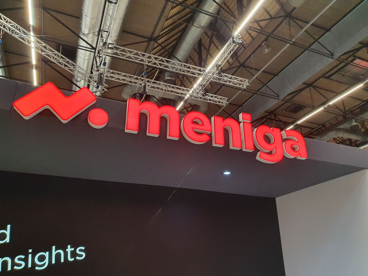 Vista del stand Meniga en RAI Amsterdam con elementos gráficos de interfaz y espacio de reuniones