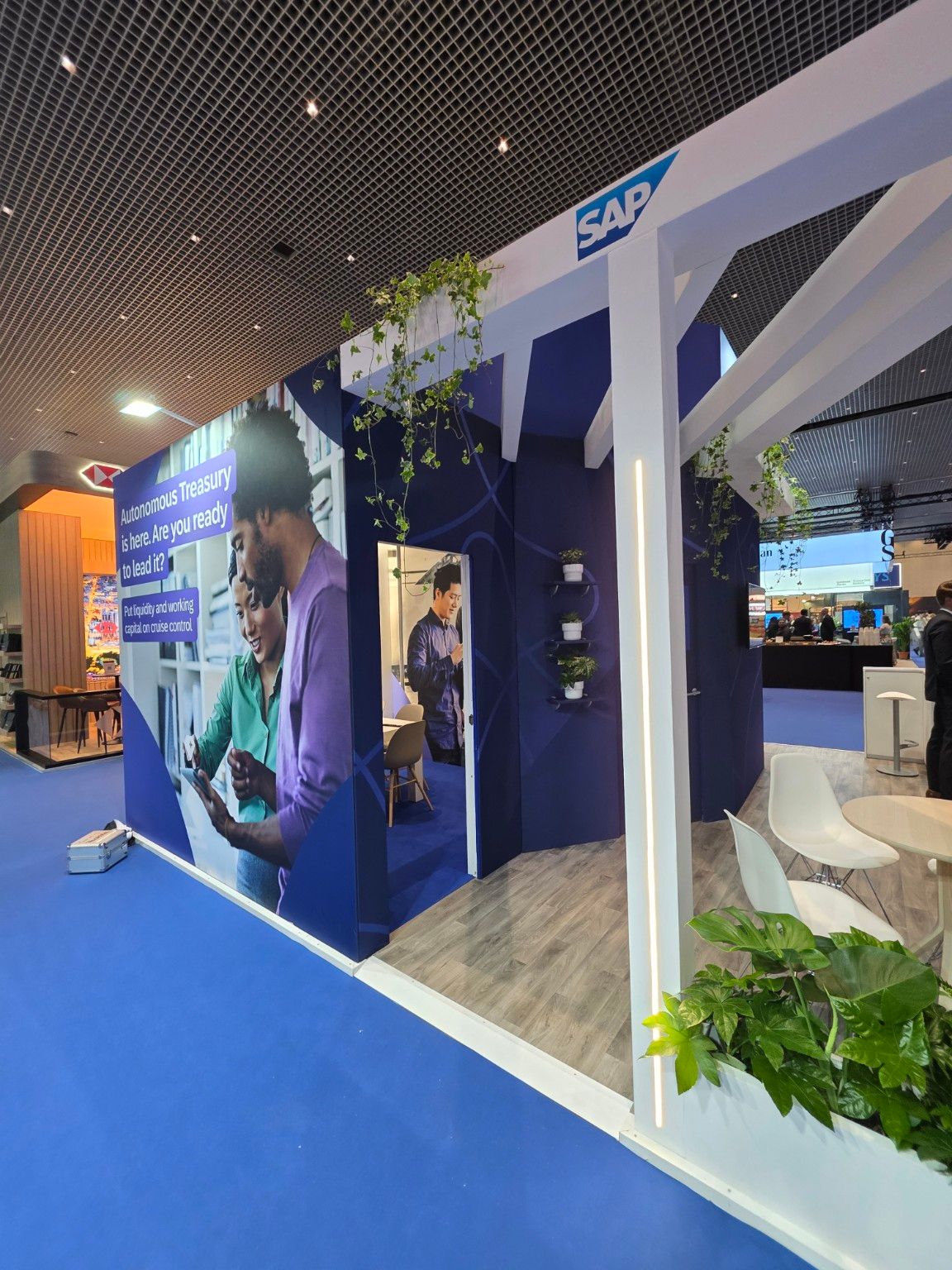 Meeting room entrance and detail of the white structure with greenery at the SAP Taulia stand