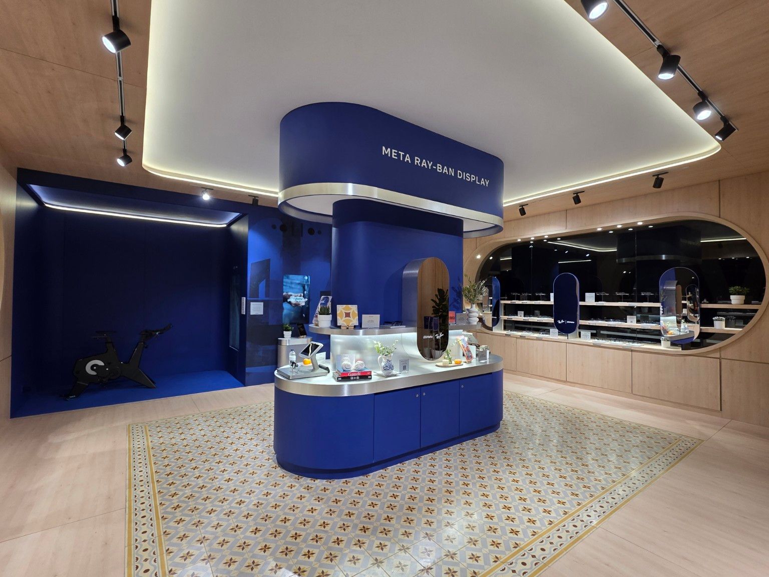 Overview of the Meta interior with a blue island, geometric floor pattern and oval display window