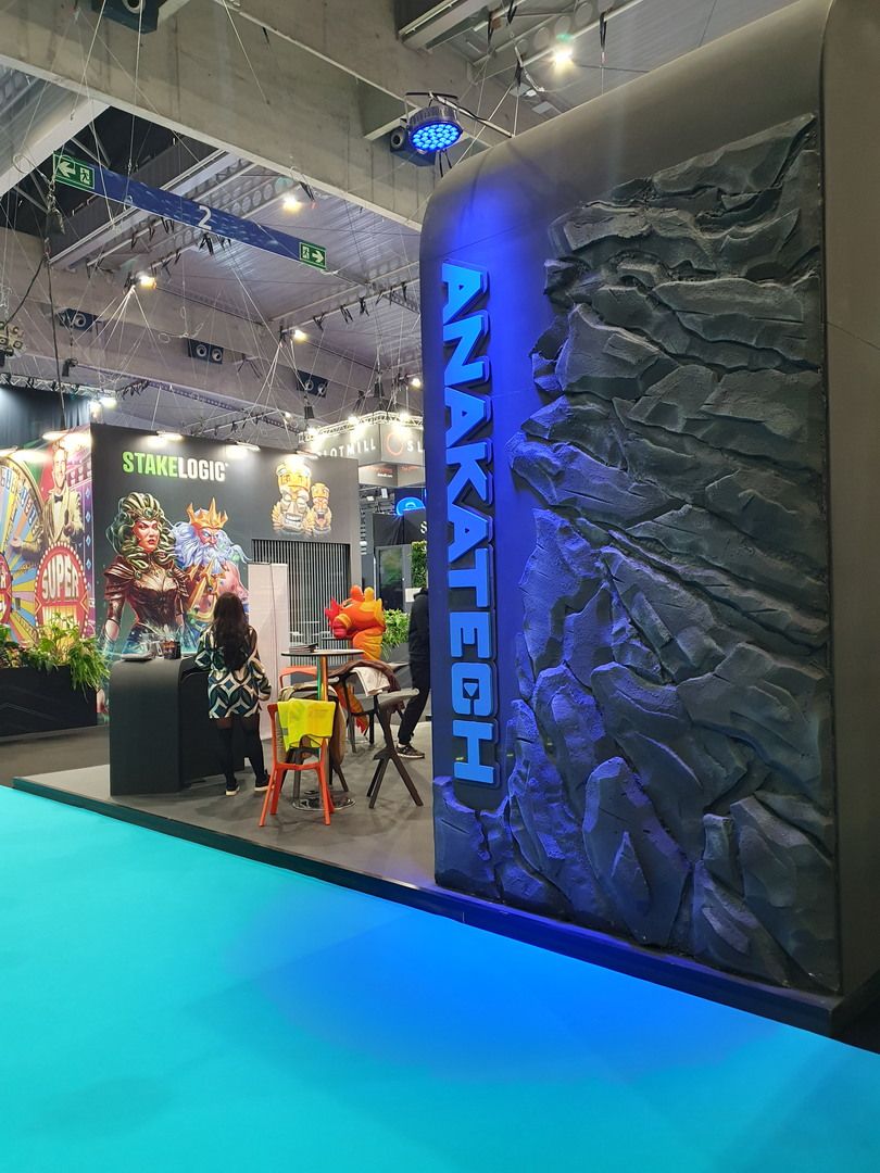 Side wall with rock relief and vertical Anakatech branding under blue lighting