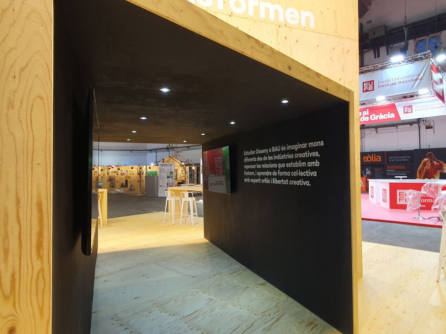 Interior oscuro del paso central con textos. BAU, Saló de l’Ensenyament 2022, Barcelona.