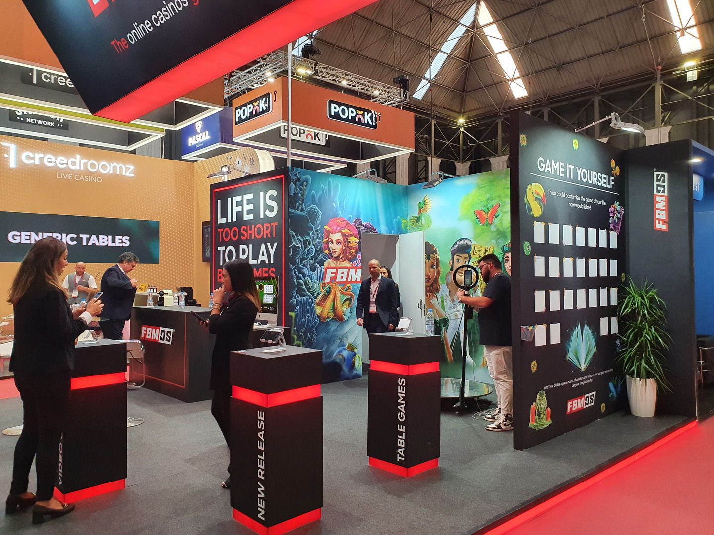 Pedestales de demostración con tabletas y frentes negros y rojos en el stand de FBM