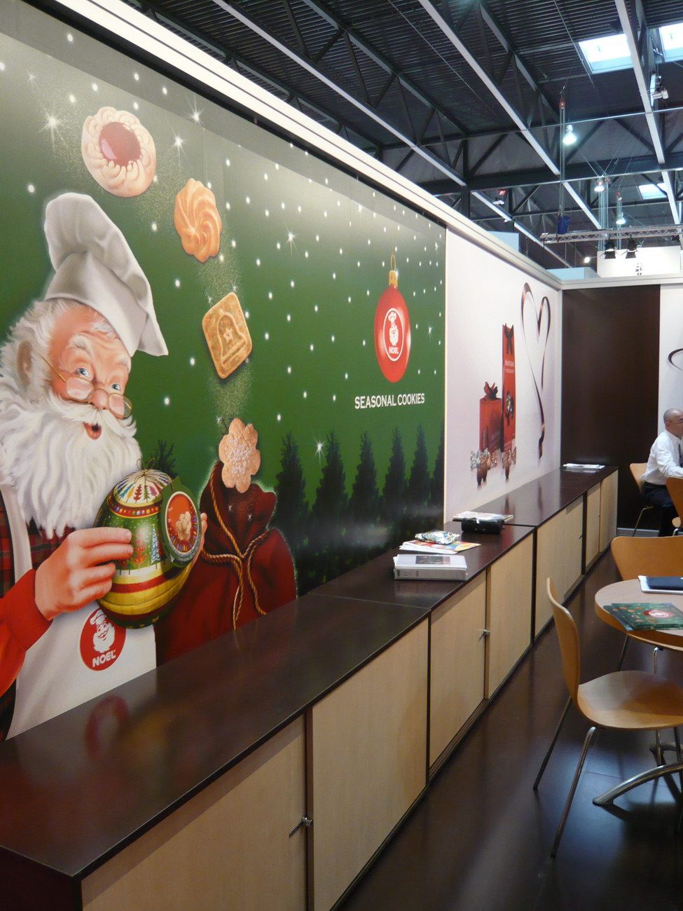 Display furniture and tables beside brand graphics — Noel