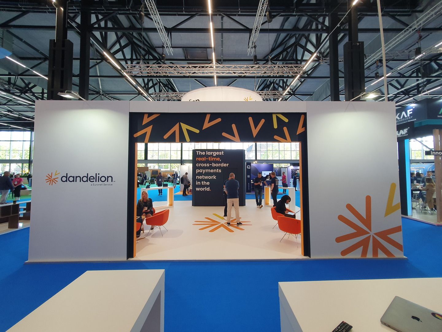 Dandelion stand at Money20/20 Europe 2023 in Amsterdam with orange branding and suspended circular sign