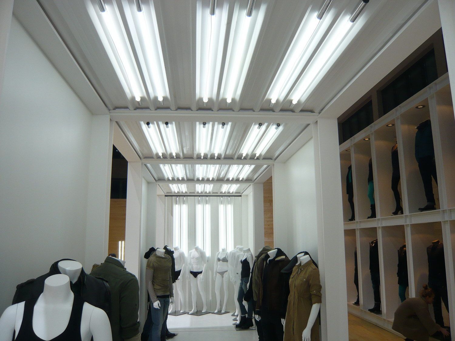 Clothing displays beneath linear lighting — Calvin Klein Jeans · Bread & Butter 2011