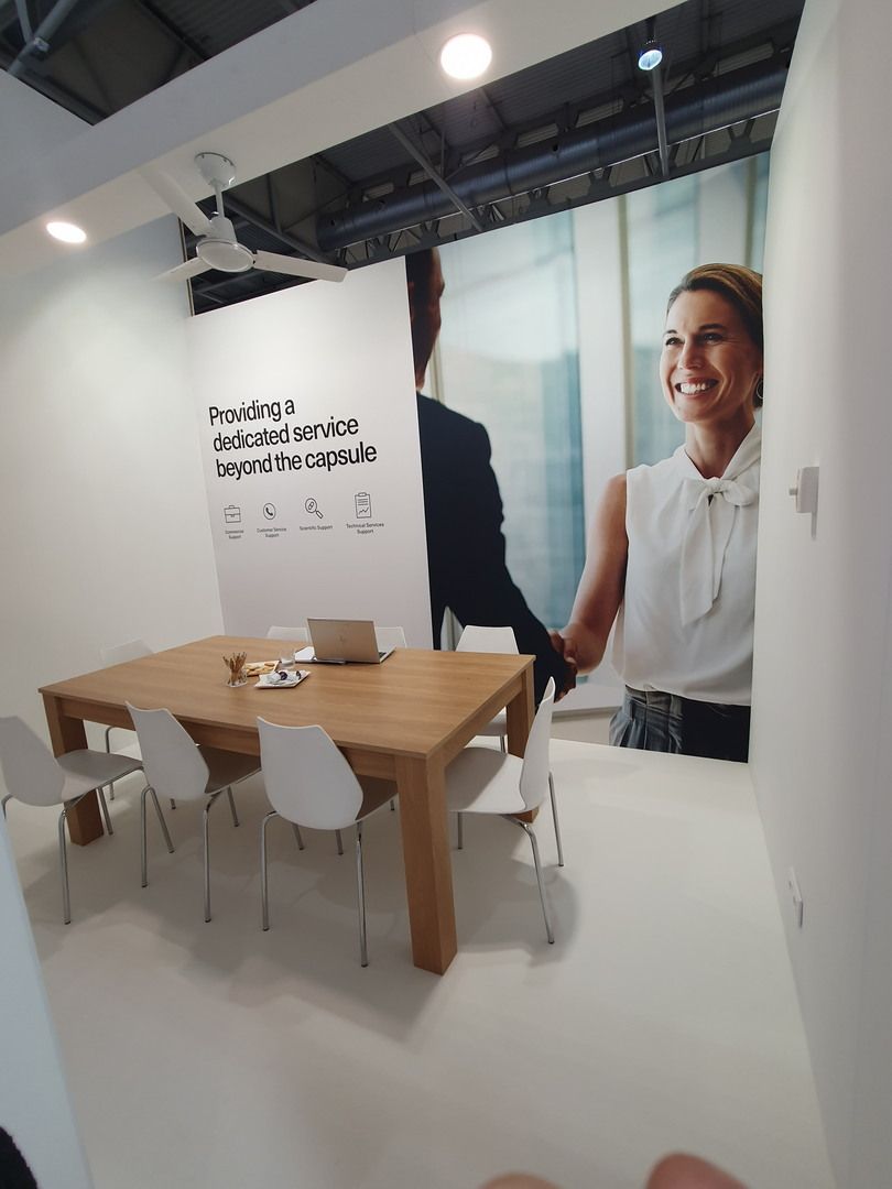 Meeting table beside graphic panels — Qualicaps · CPHI