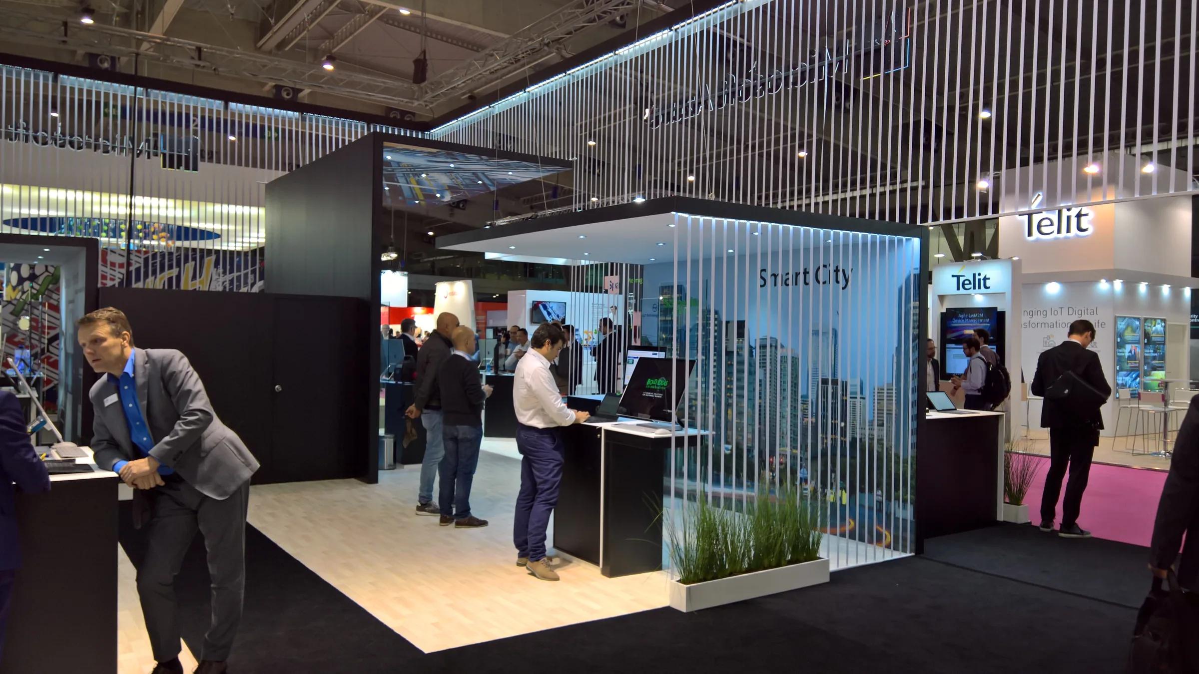 Interior del stand con zonas de demostración y estructura suspendida · IoT 2018