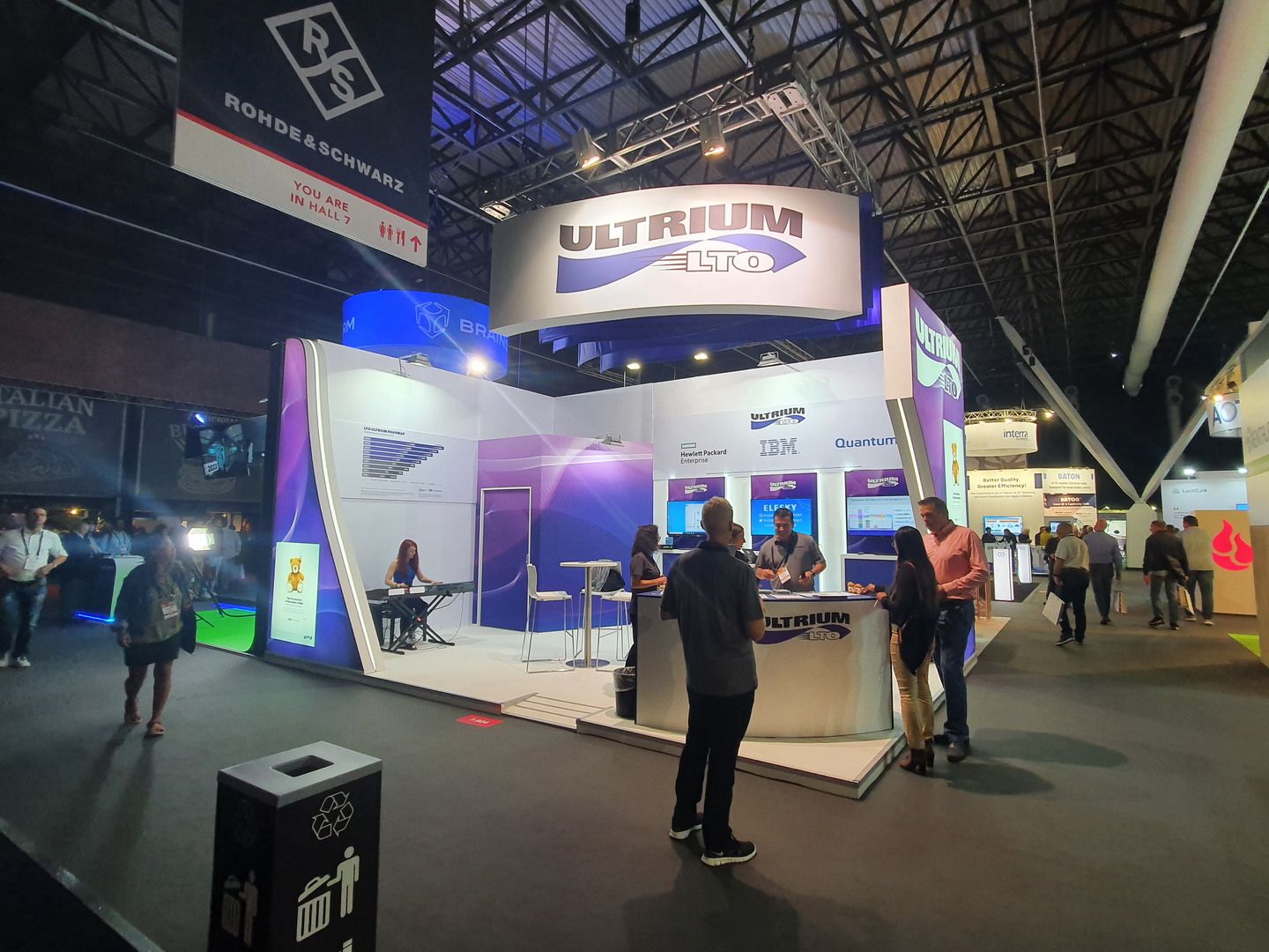 Stand tecnológico de LTO en IBC Amsterdam 2022 con identidad púrpura y áreas de demostración