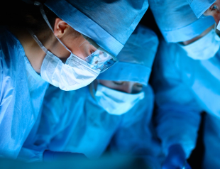 Three surgeons looking closely at patient