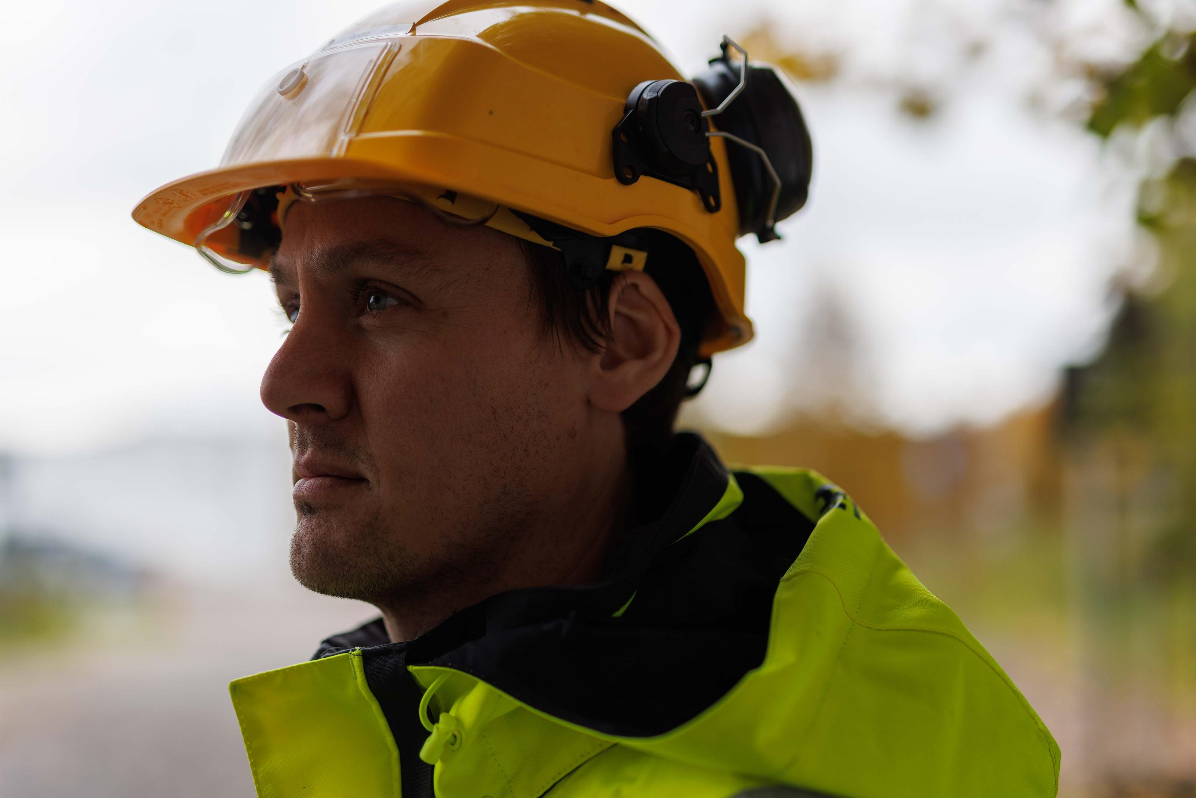 Profilert sidevisning av bygningsarbeider med gul hjelm og høysynlig vest