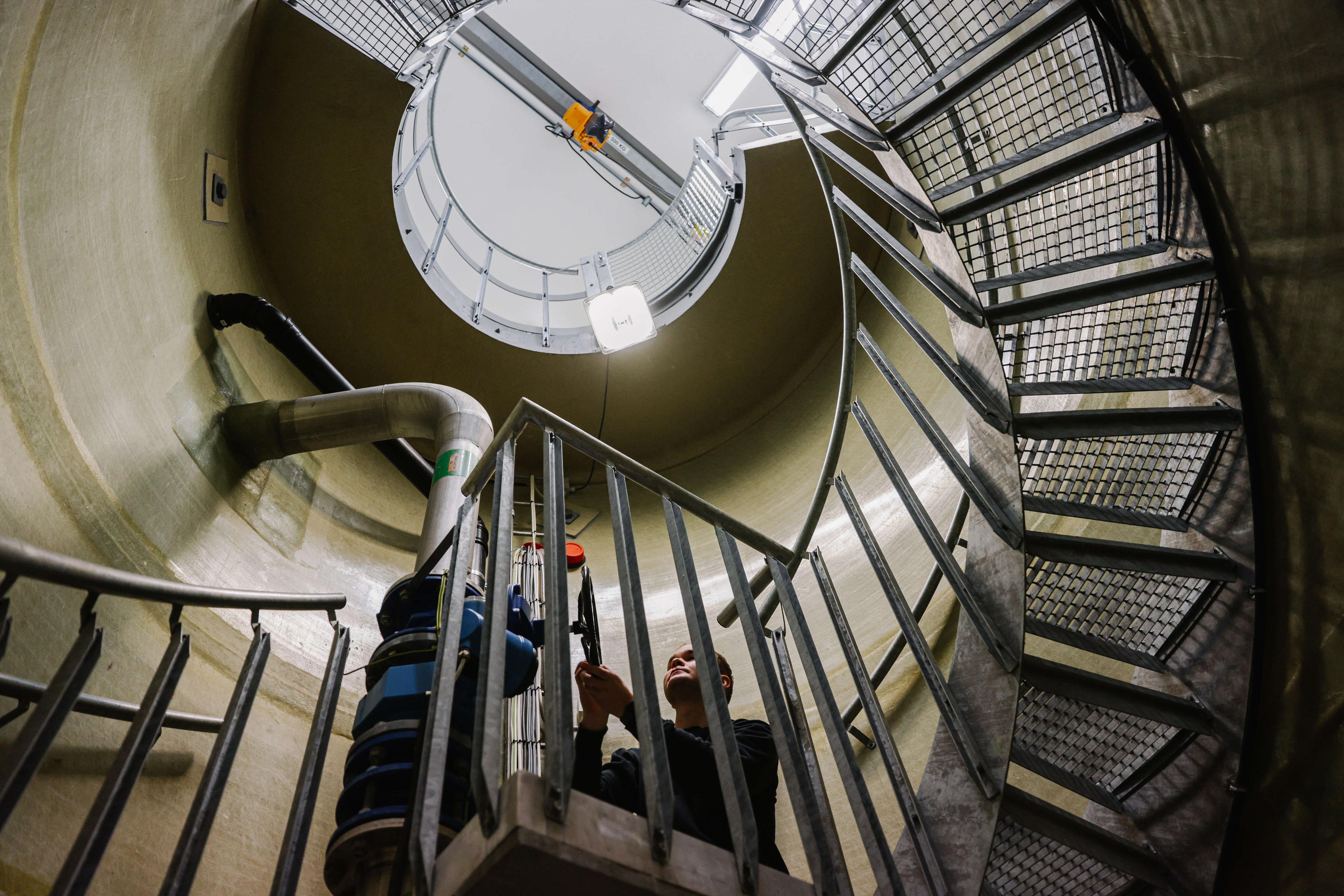 Spiraltrapp i industribygg sett nedenfra med person som kikker opp mot taket.