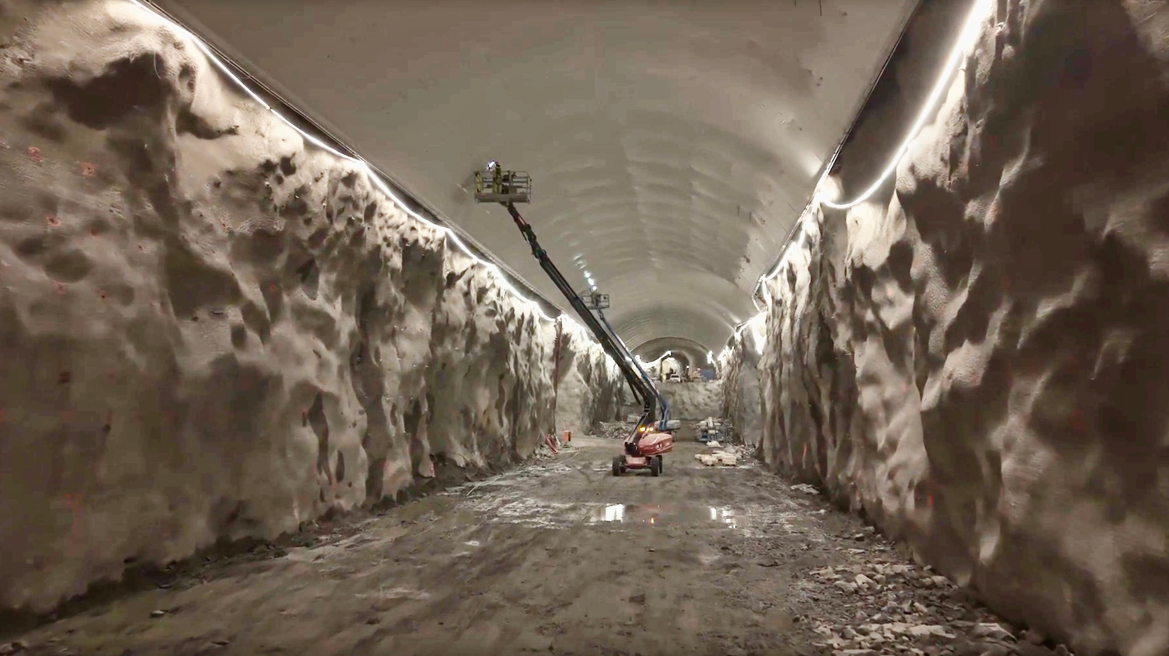 En lift med en person som fester en duk i taket på en tunnel.