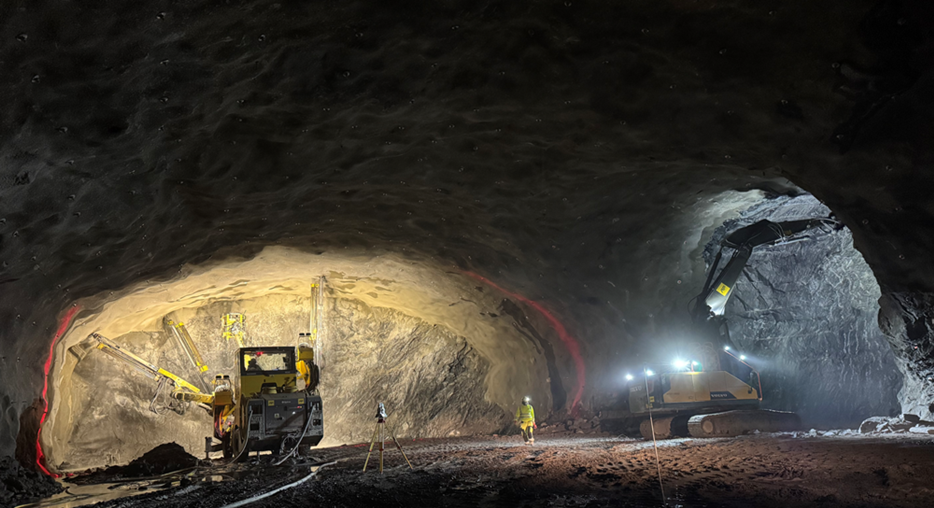 Anleggsmaskiner driver ut tunnel.
