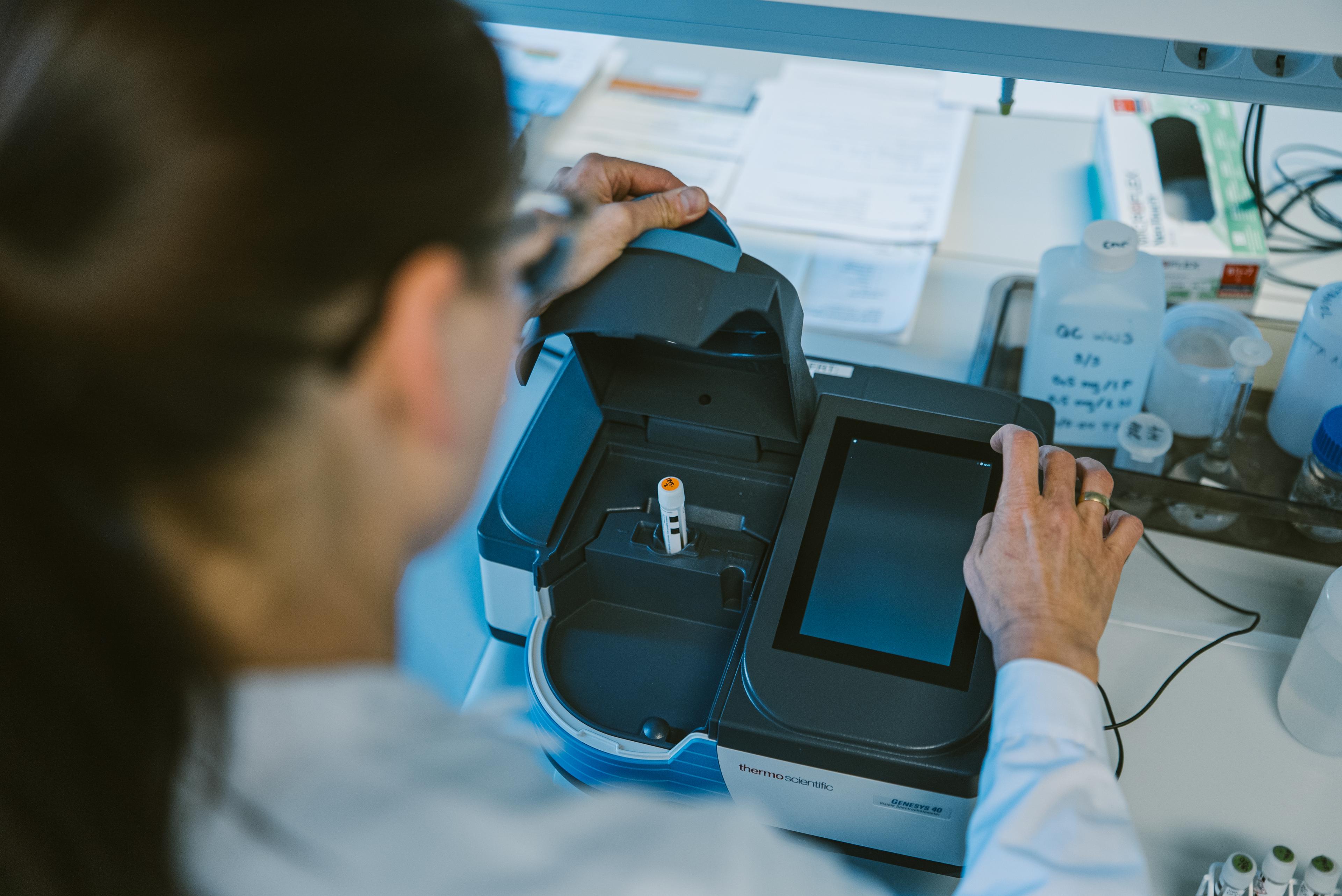 Laboratoriearbeider betjener et digitalt analyseinstrument i et forskningslaboratorium