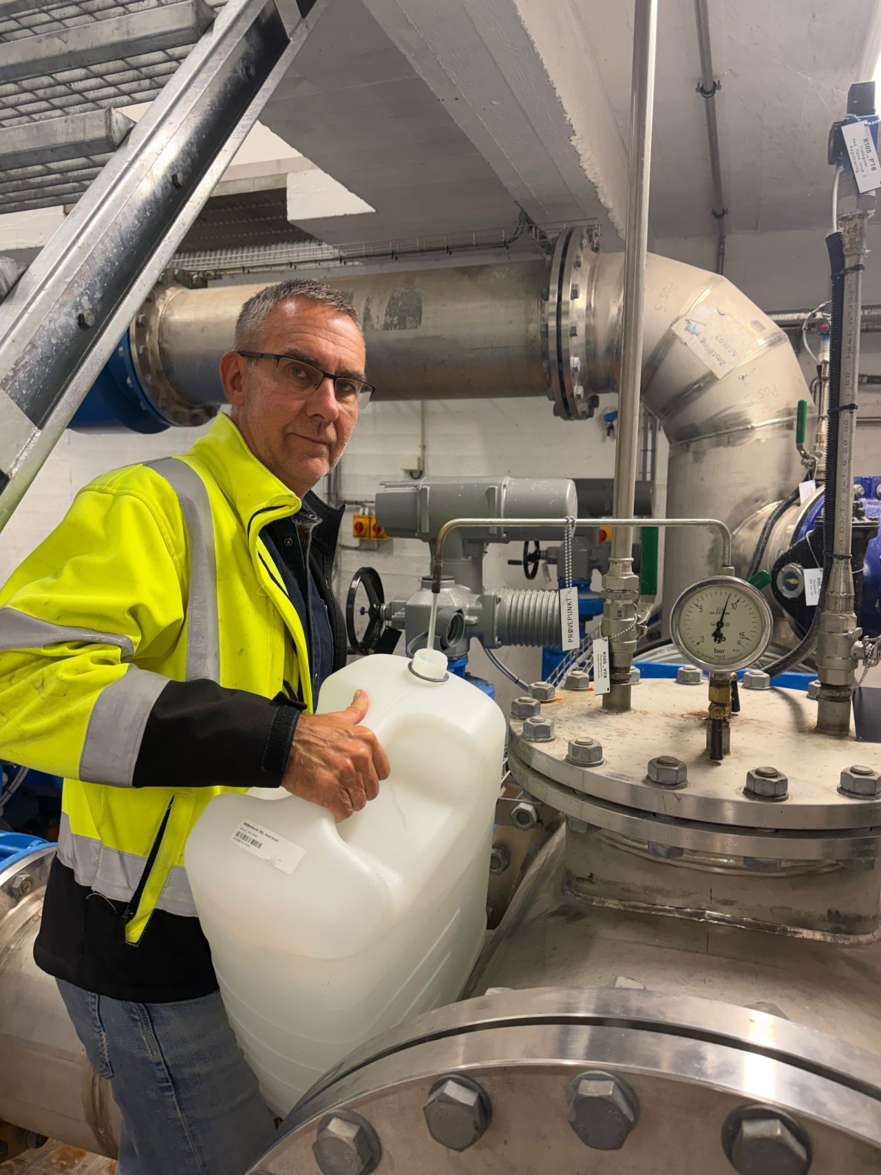 Mann står med stor vanndunk inne i vannverk.