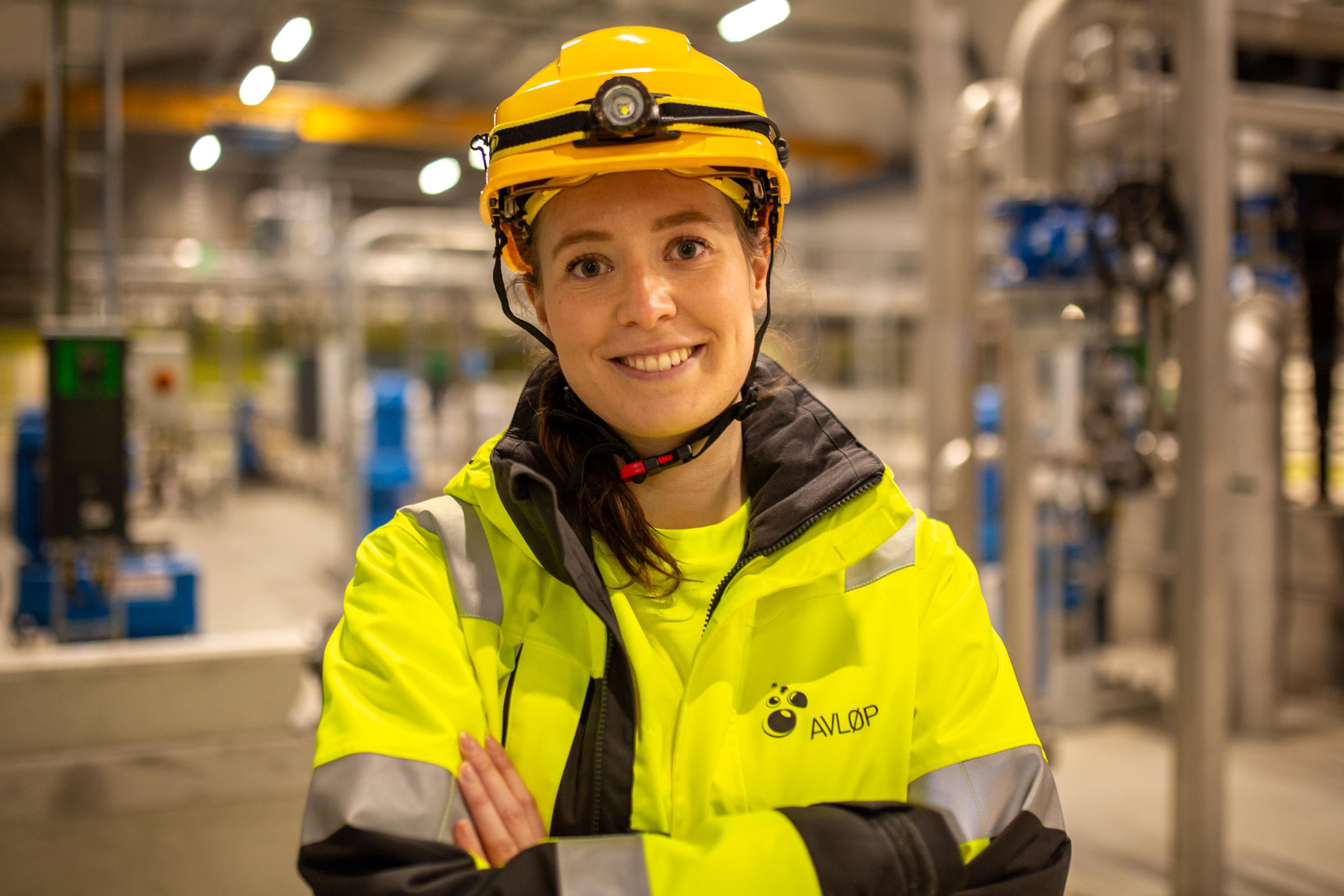 Kvinne med signalgule verneklær på innsiden av renseanlegg.