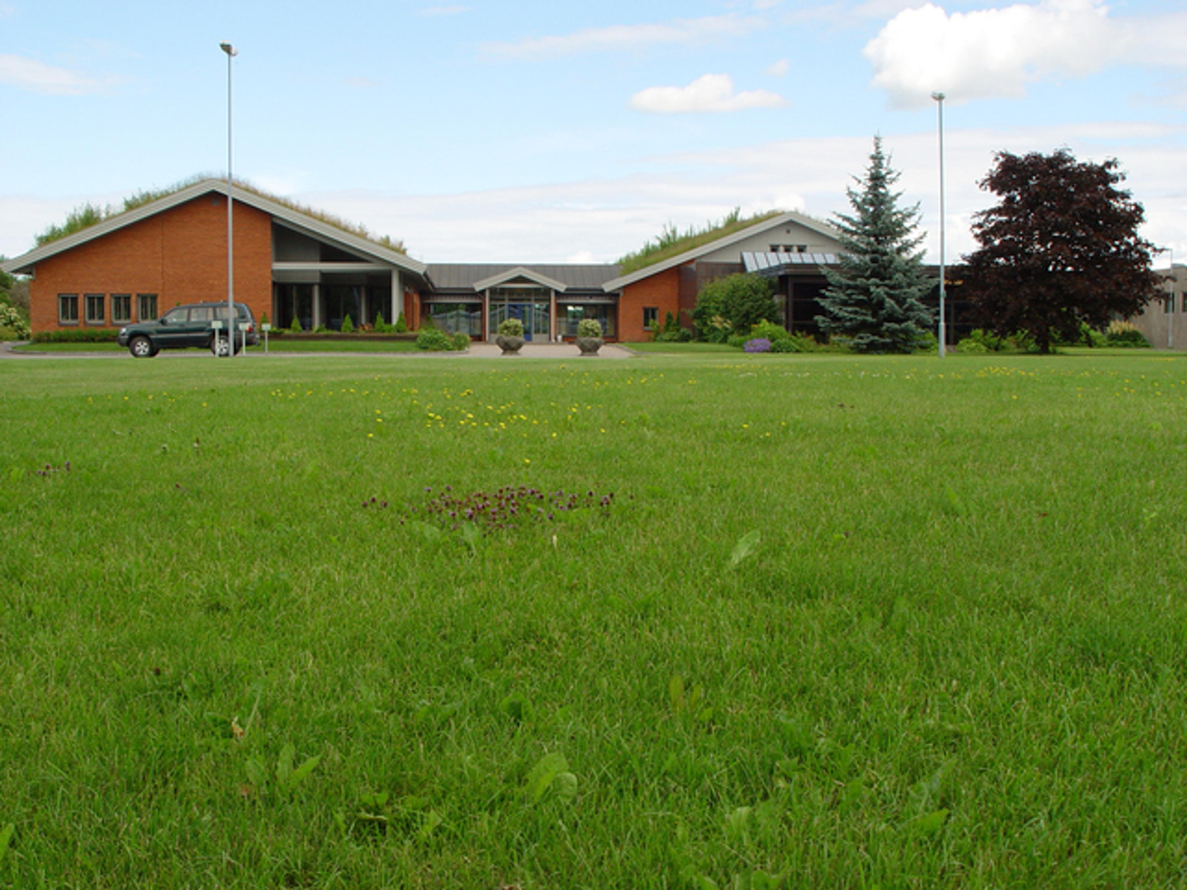 Strandveien kirke med grønn plen i forgrunnen og trær i bakgrunnen