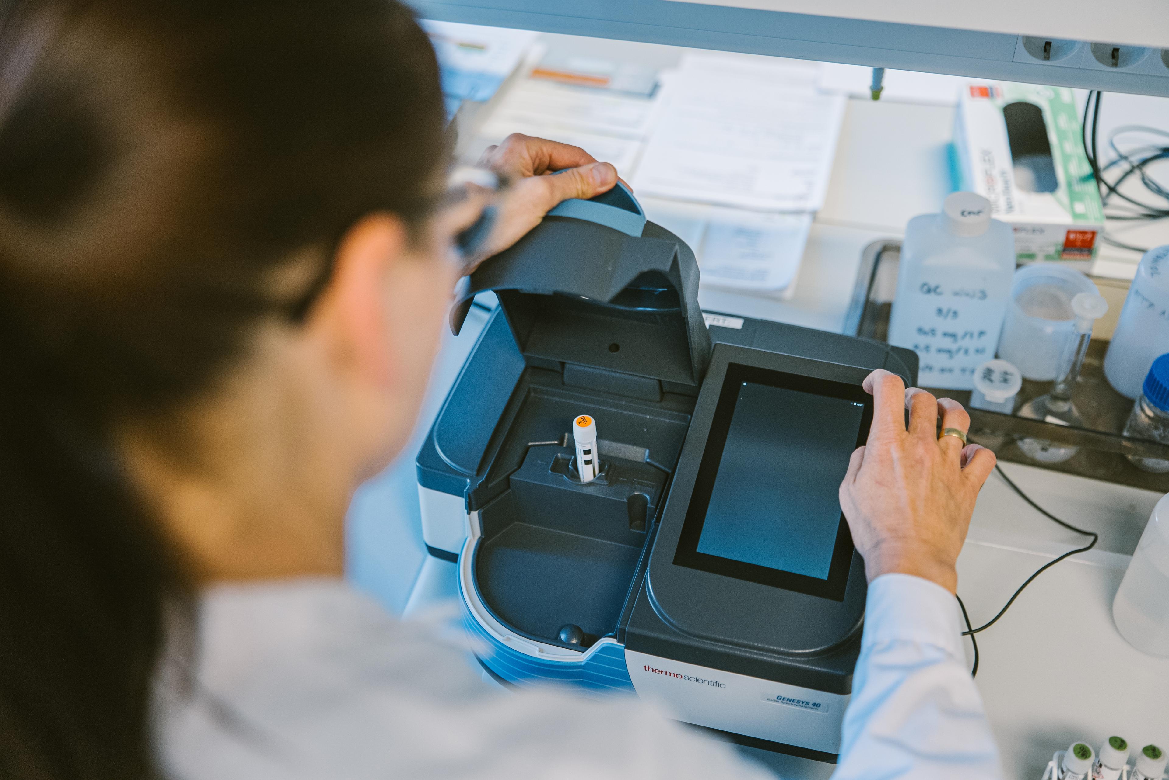 Laboratorietekniker betjener vitenskapelig analyseutstyr med digitalt display