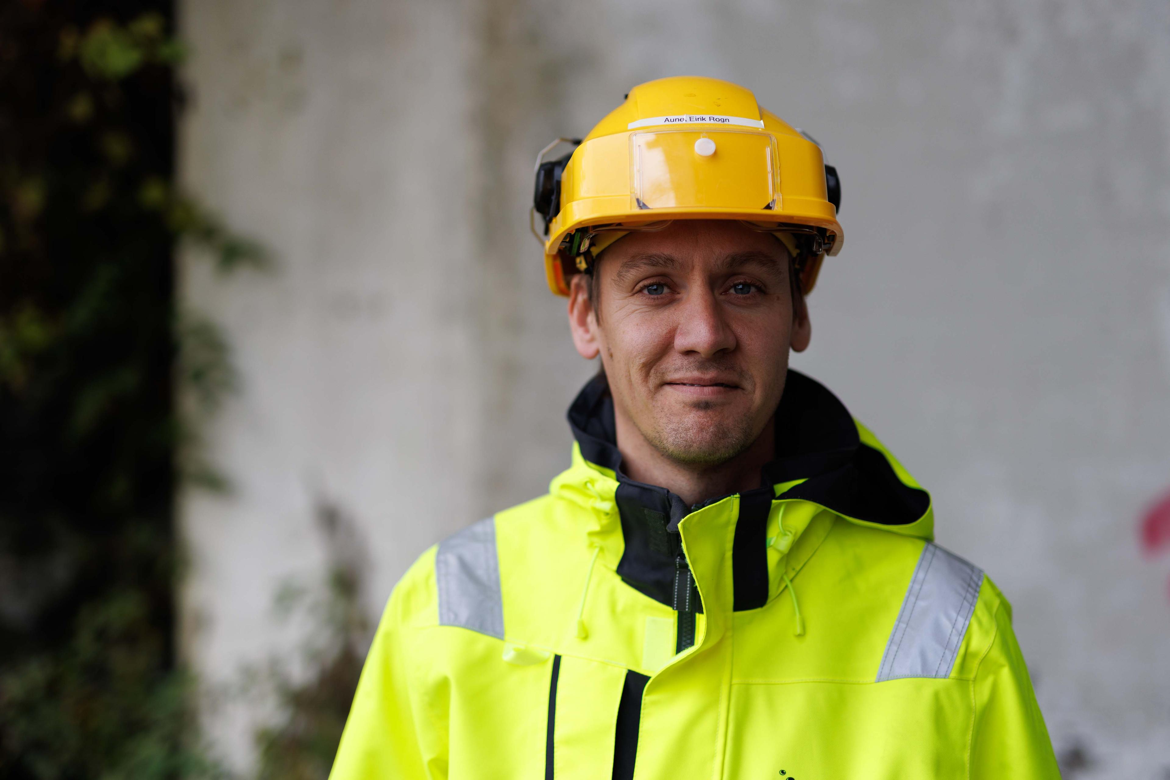 Nærbilde av vennlig bygningsarbeider med gul hjelm og refleksvest