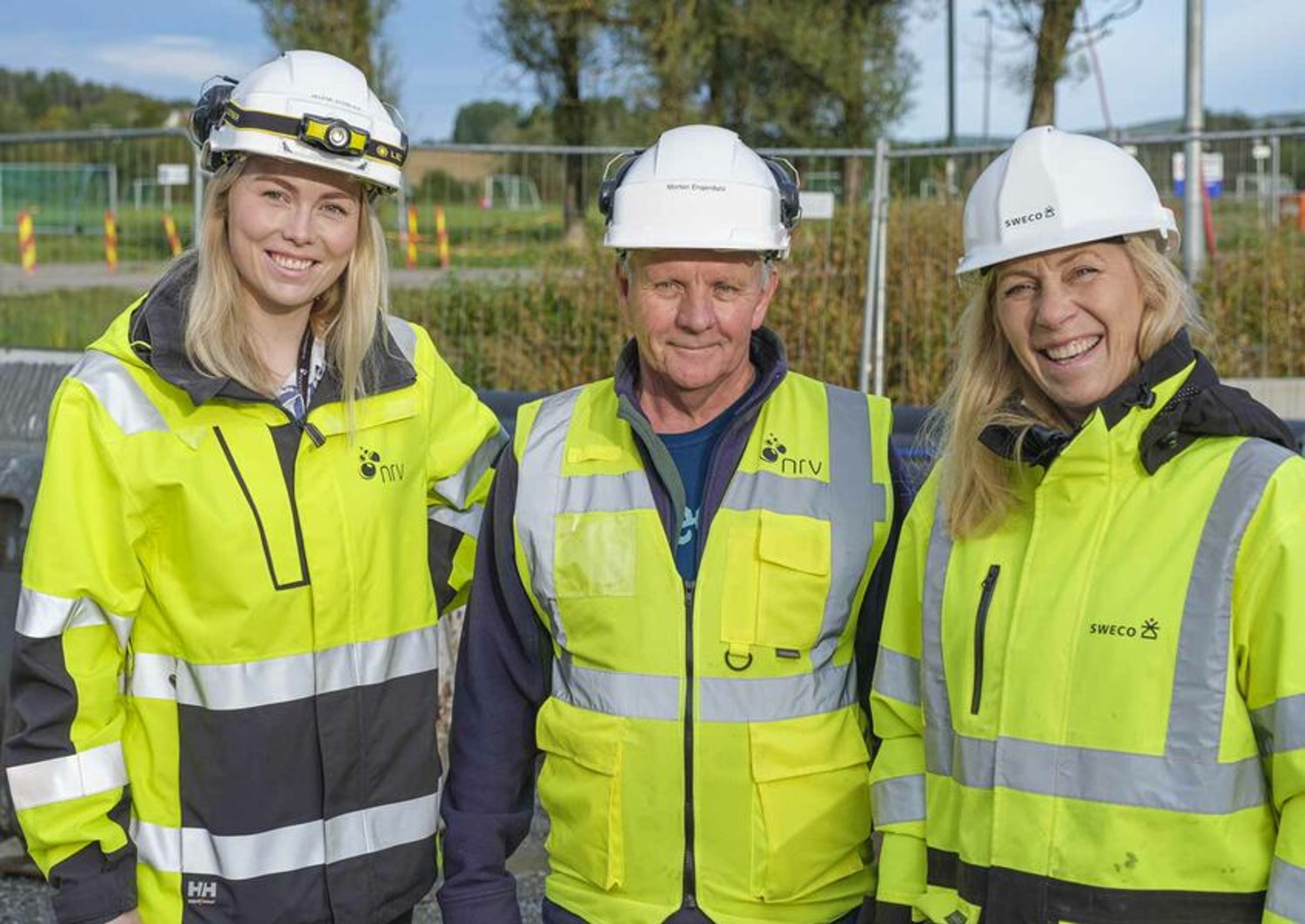 Tre anleggsarbeidere med hjelm og gul refleksvest