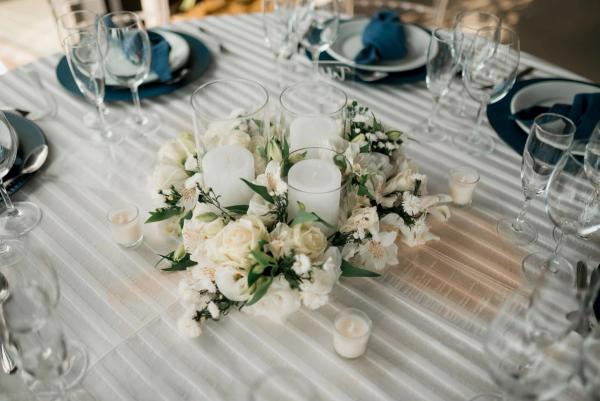 Mesa de banquete montada con centro de flores blancas y velas
