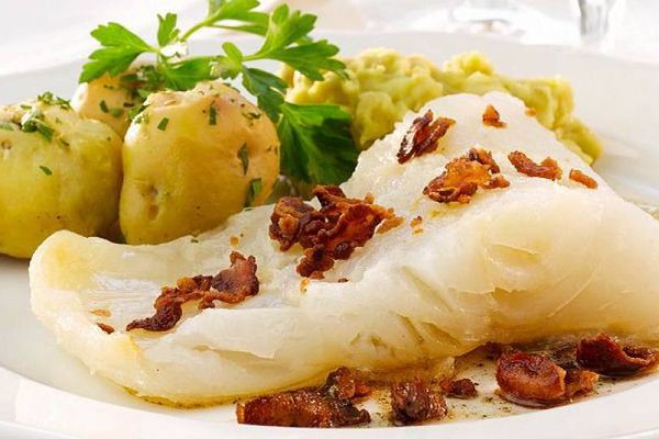 Lutefisk på tallerken med baconbiter og poteter