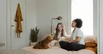 two women and a dog sitting on a bed