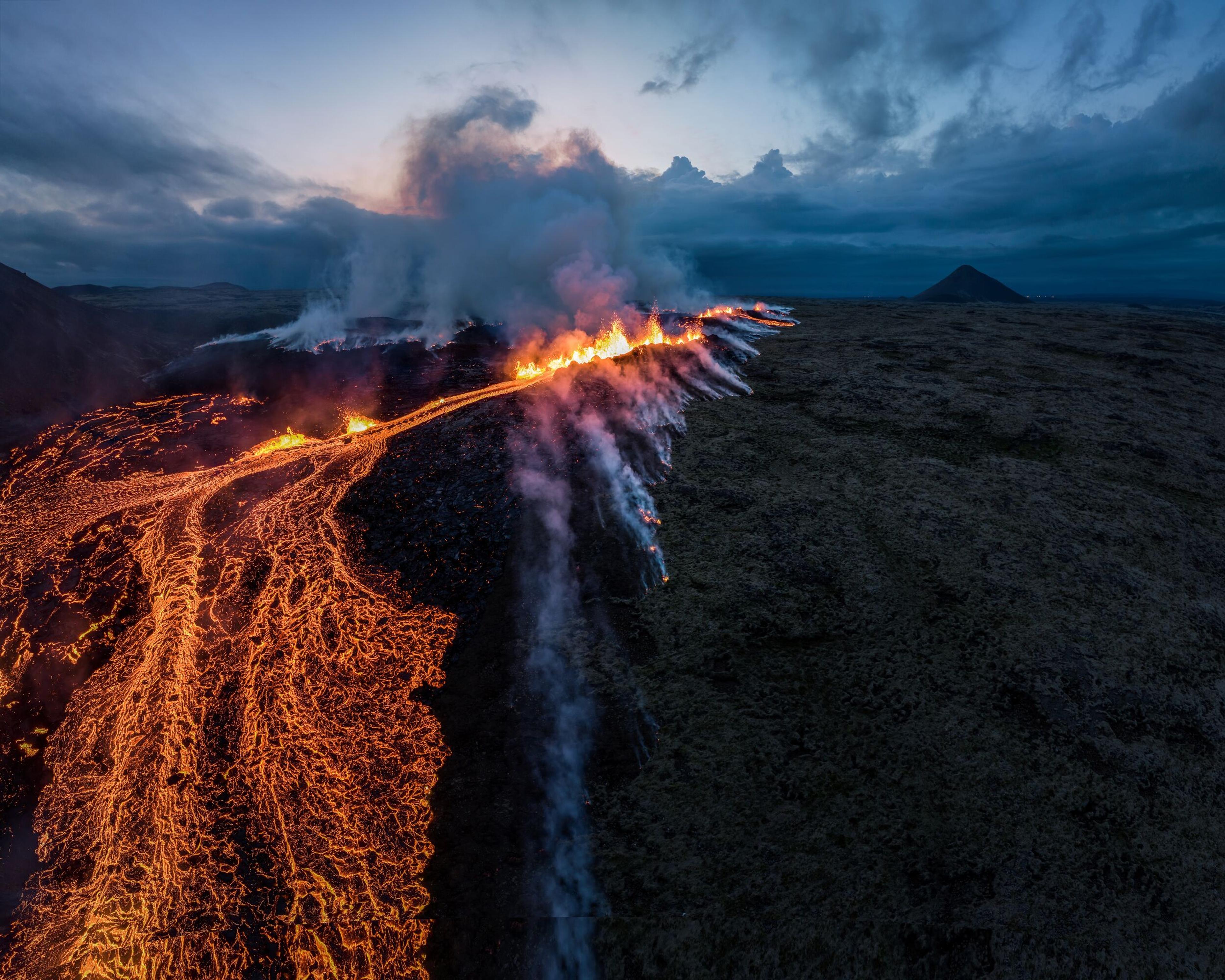 an aerial view of a volcano erupting at night .