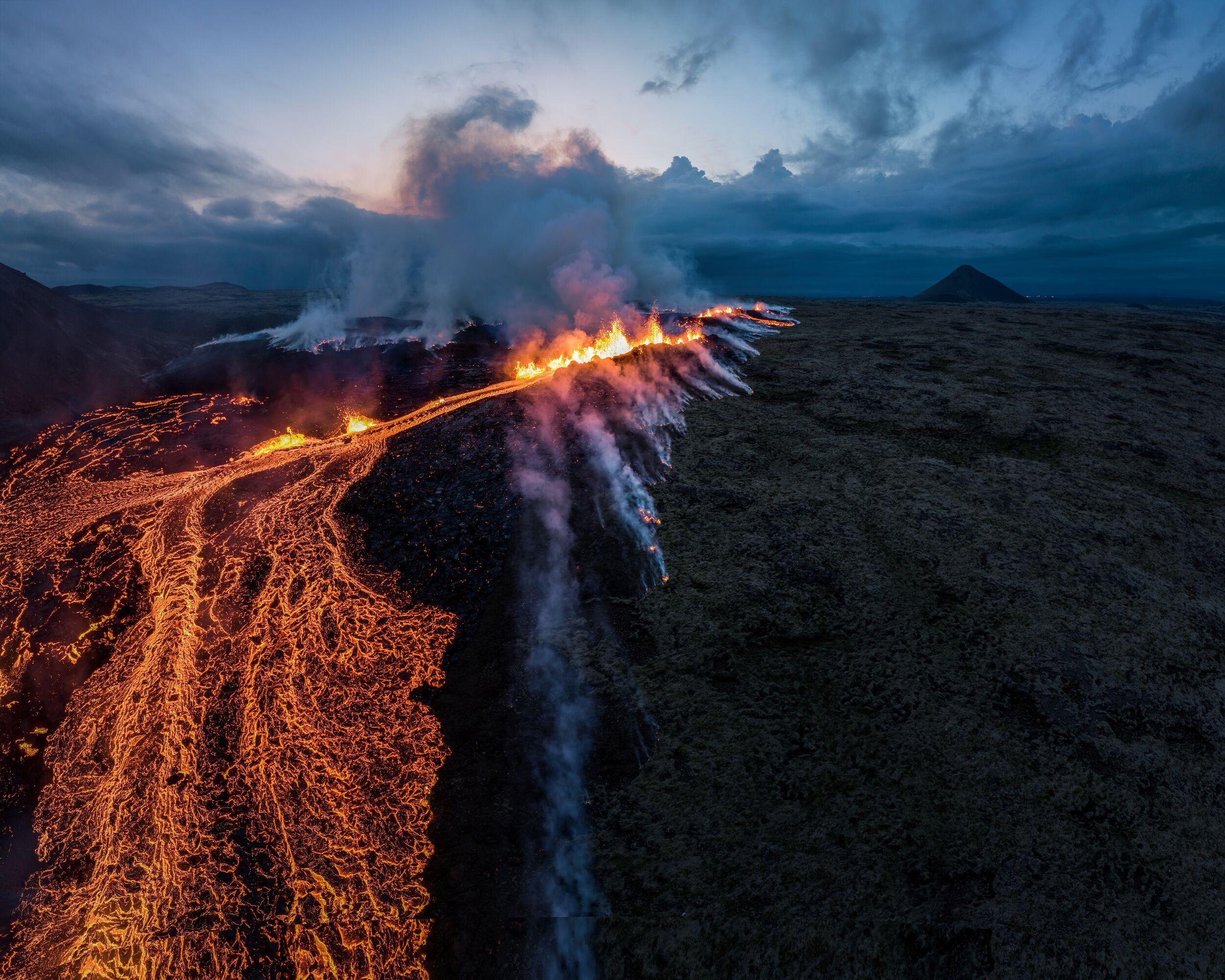 an aerial view of a volcano erupting at night .