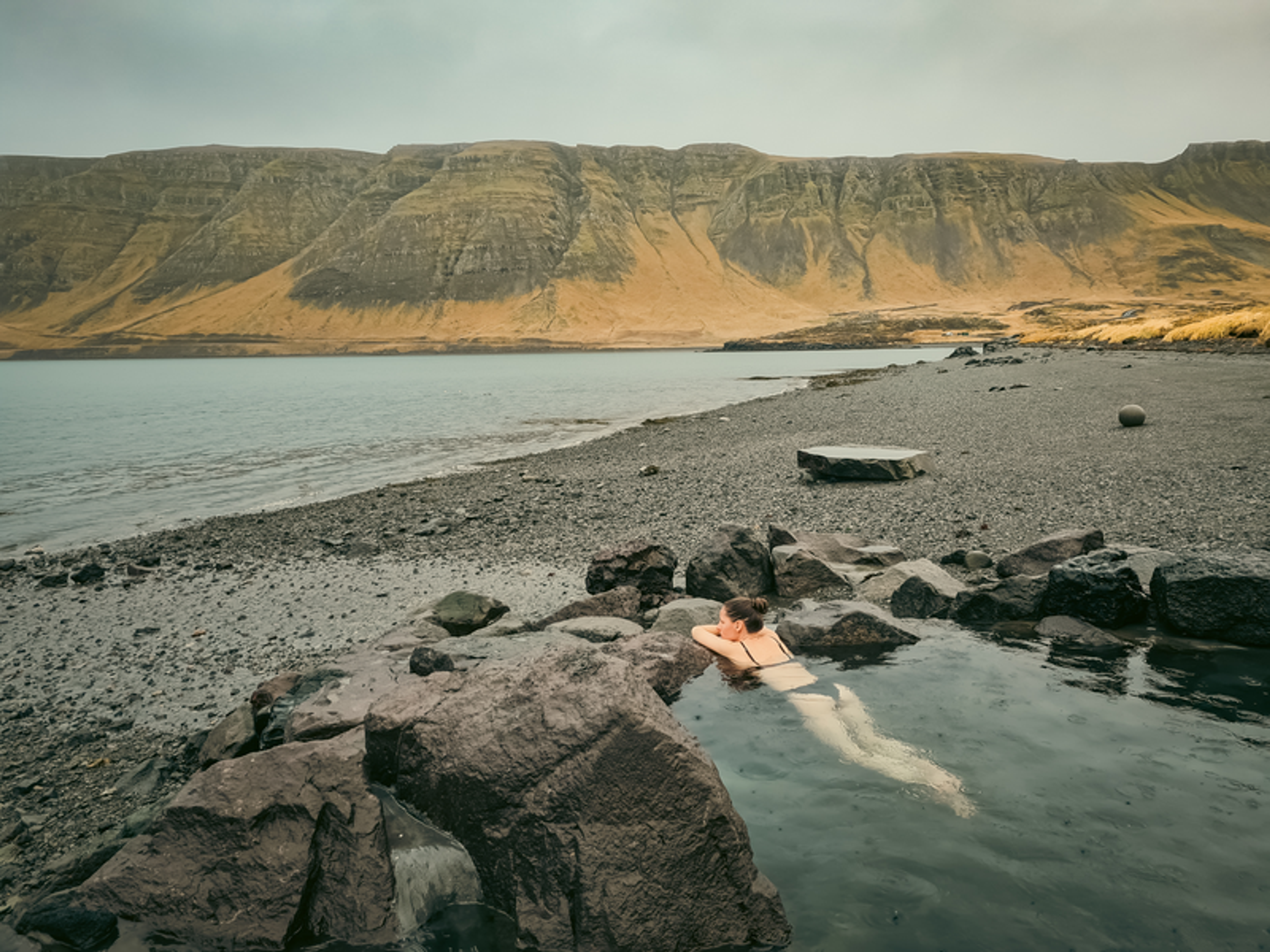 a woman is swimming in a lake surrounded by rocks