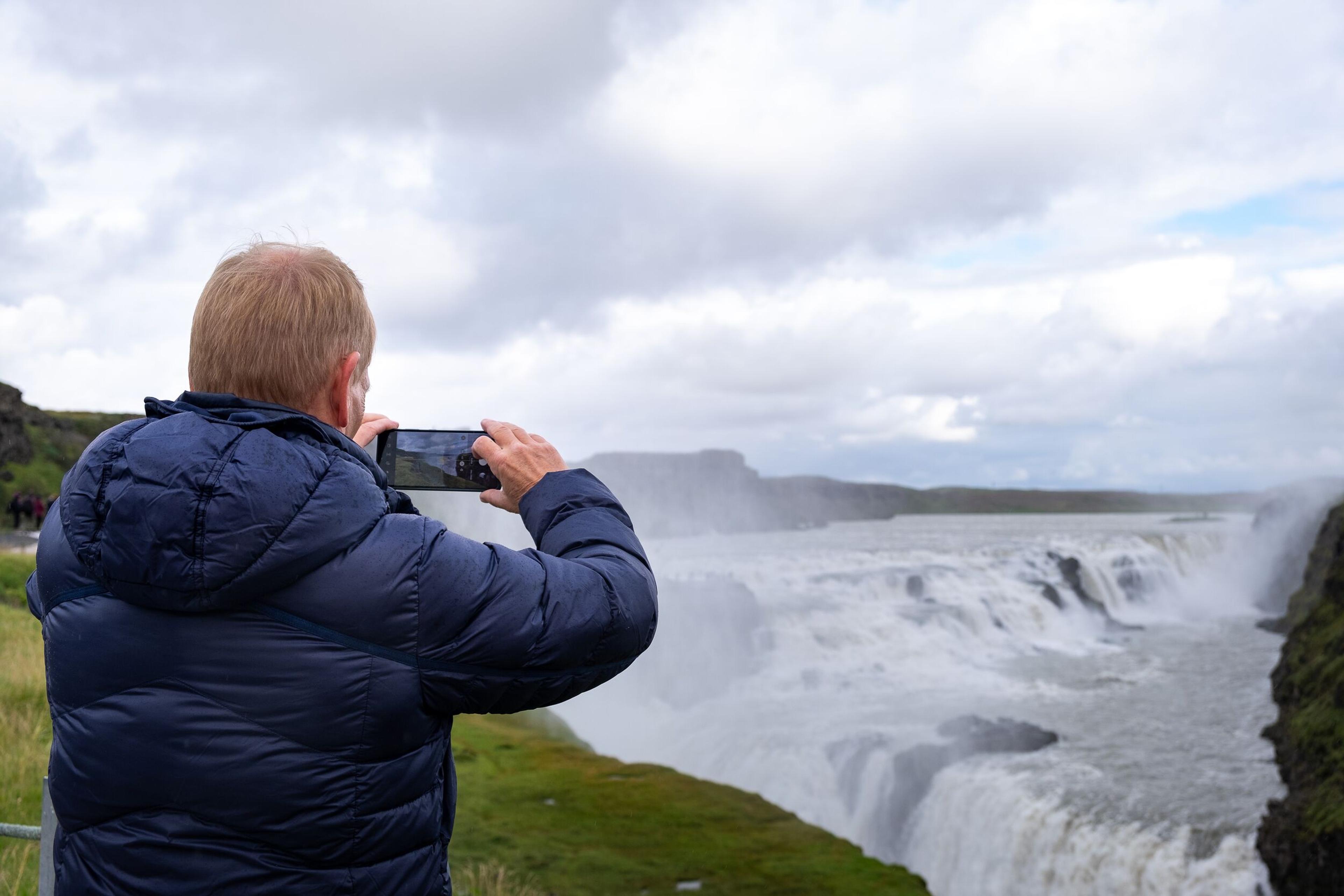 A person taking a picture at Gullfoss Waterfall in the Golden Circle in Iceland.
