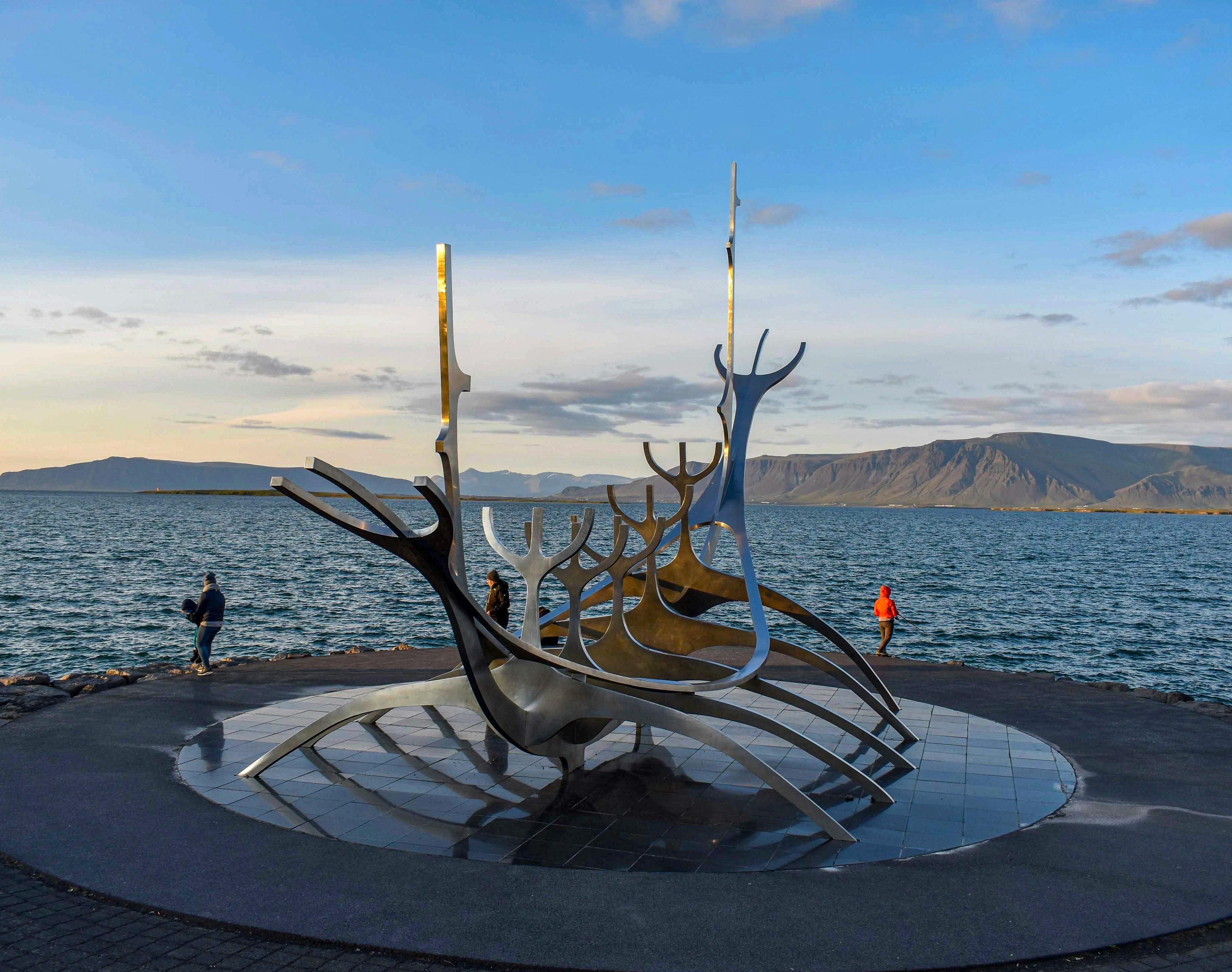 The Sun Voyager sculpture in Reykjavík, overlooking the ocean with mountains in the background.