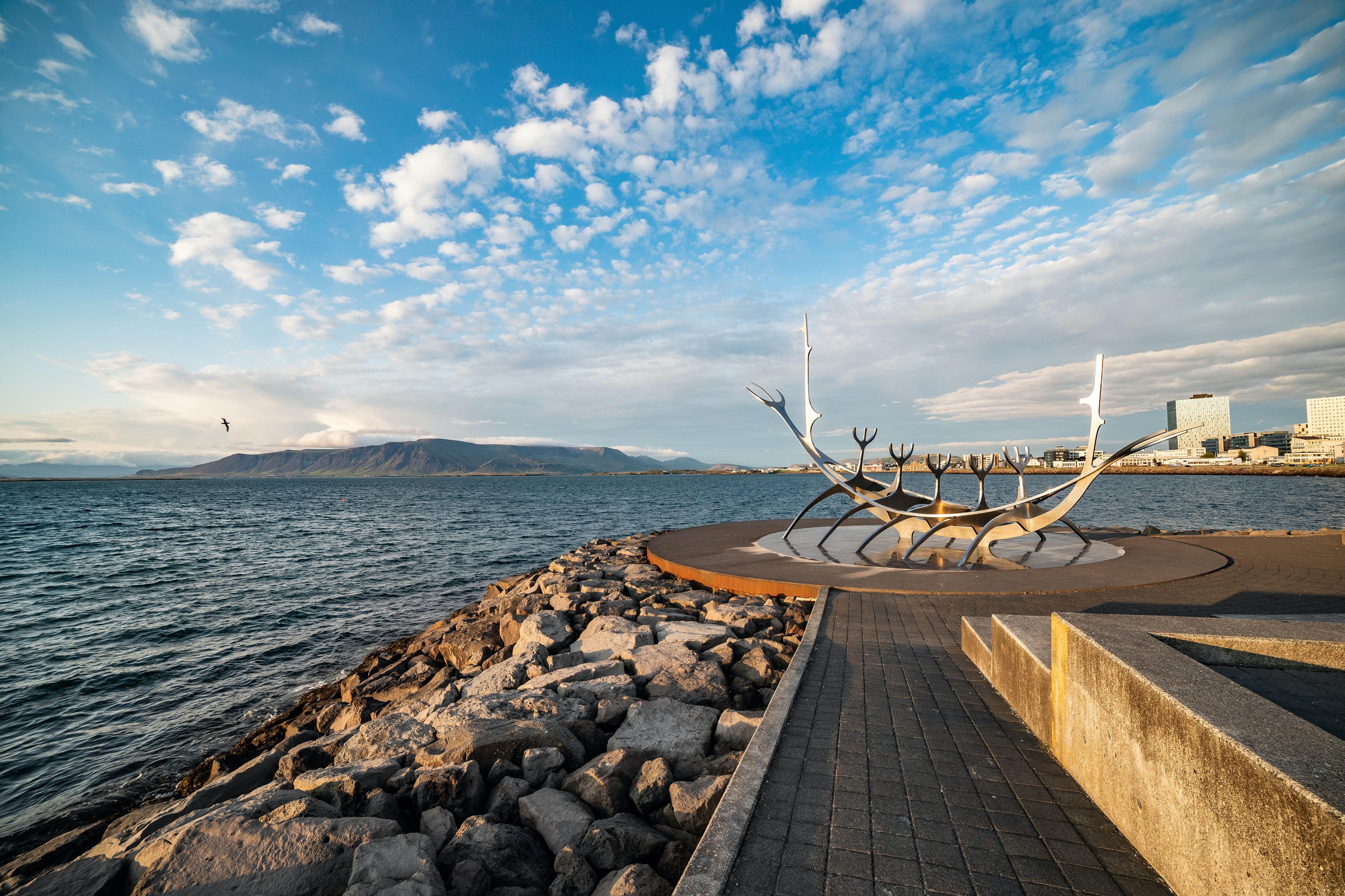 An abstract metal sculpture of a Viking boat situated beside the sea