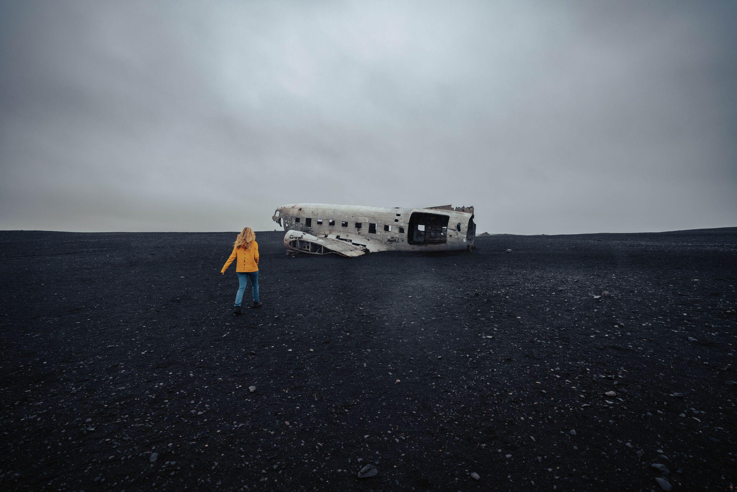 A female traveller approaching the plane wreck in the black desert