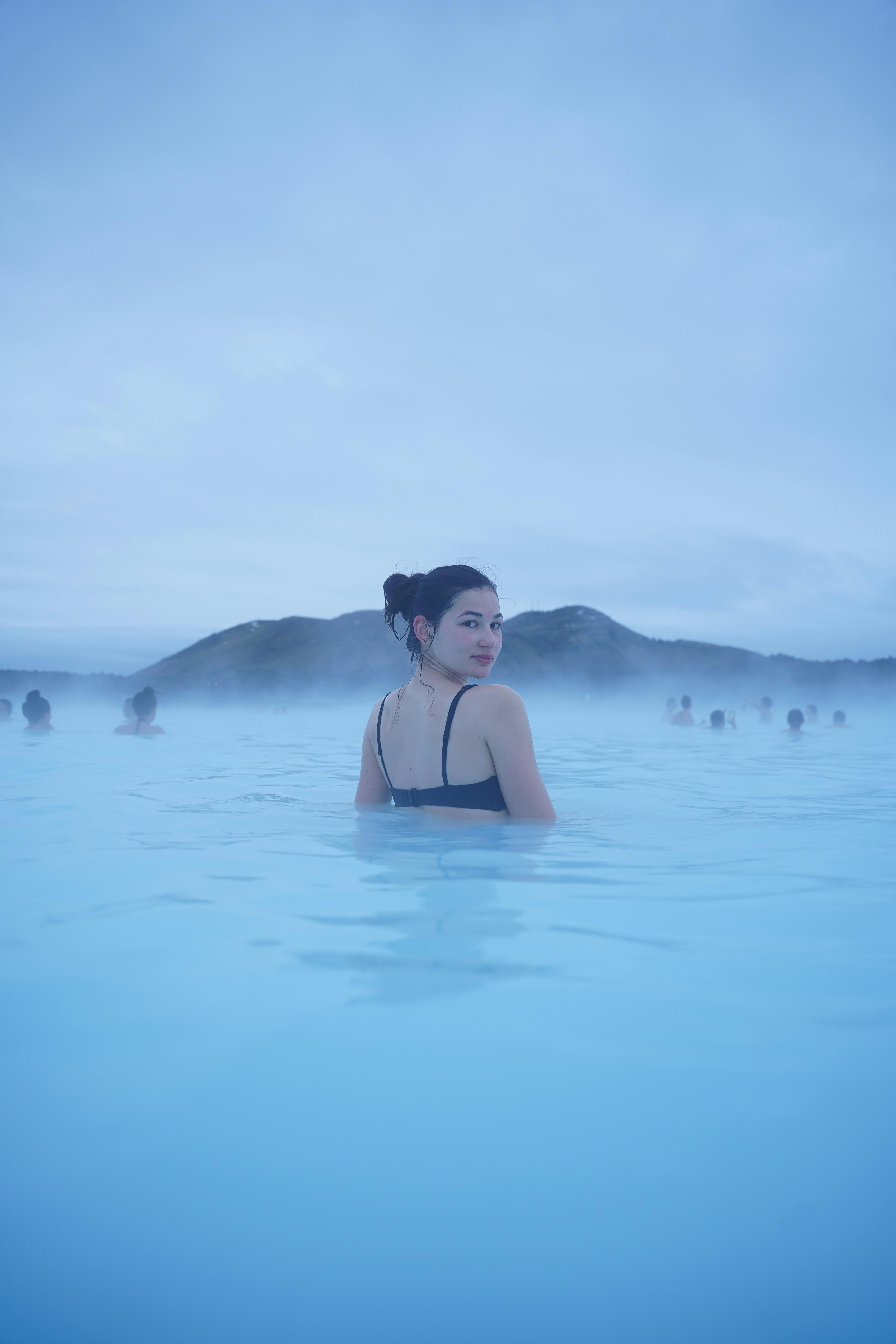 a woman in a black bikini is swimming in a blue pool .