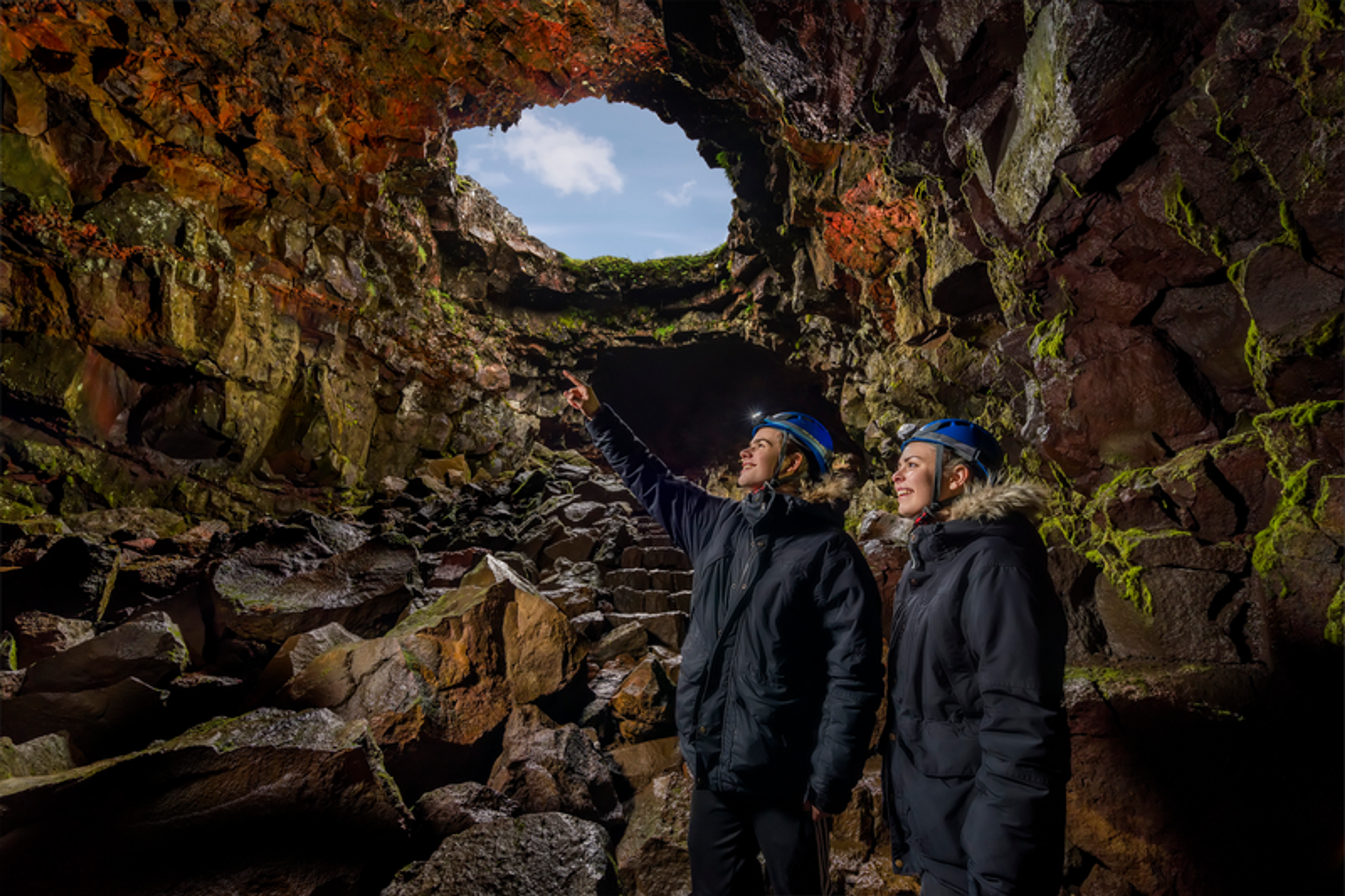 a man and a woman are looking out of a cave