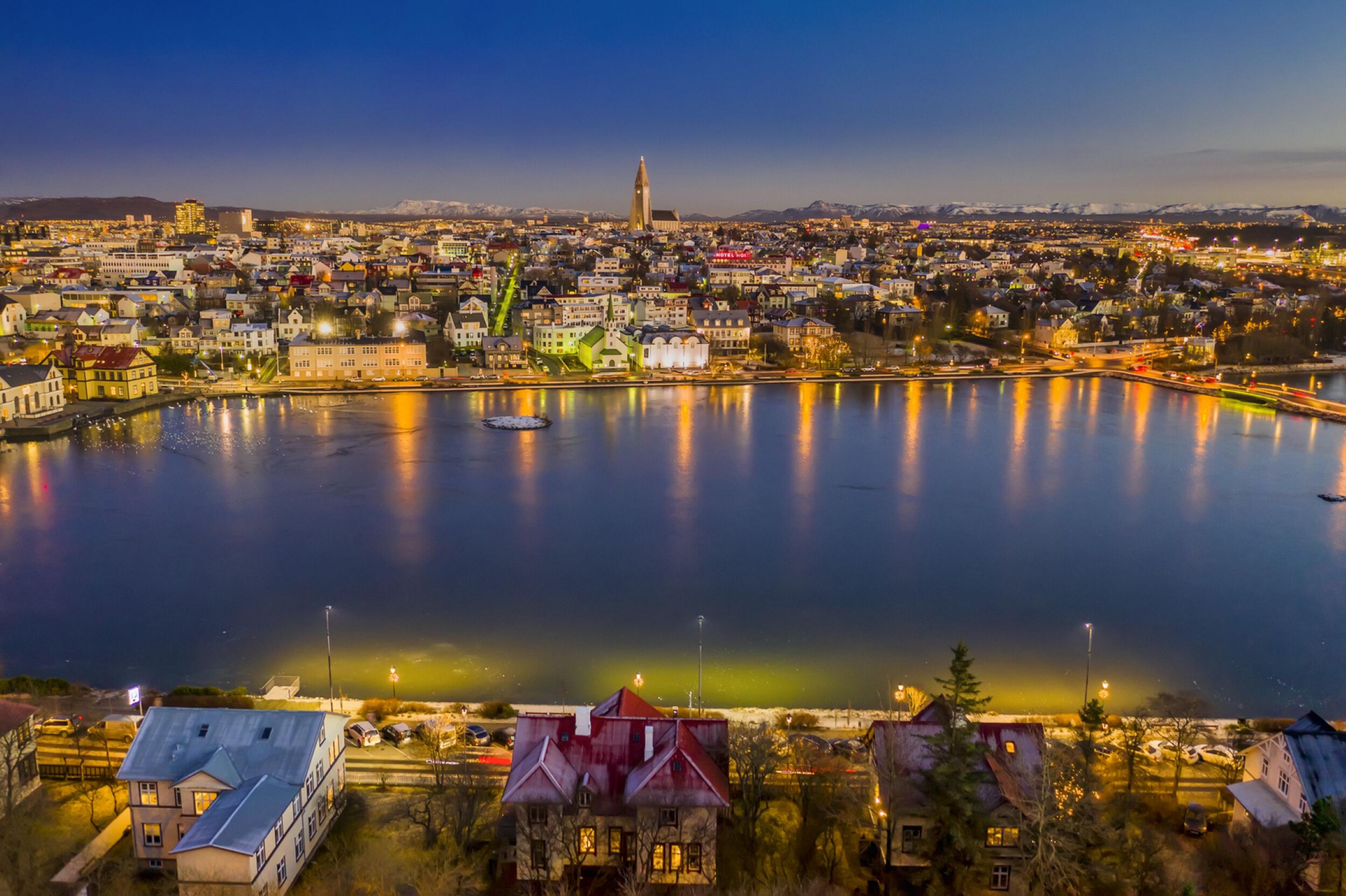 an aerial view of a city at night with a lake in the foreground .