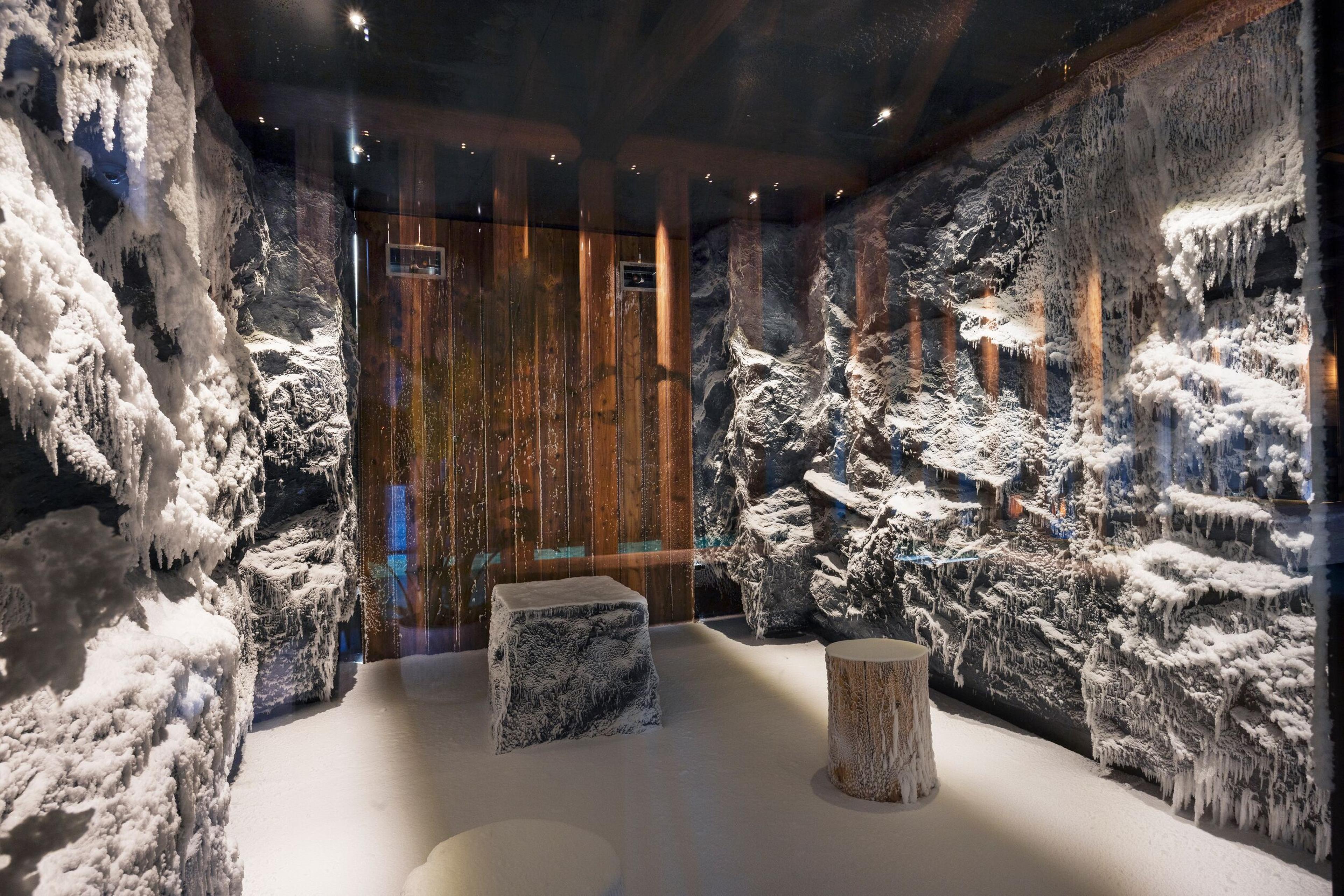 An ice room with snow and icicle-covered rock walls, a wooden back wall, a stone block, and a tree stump.