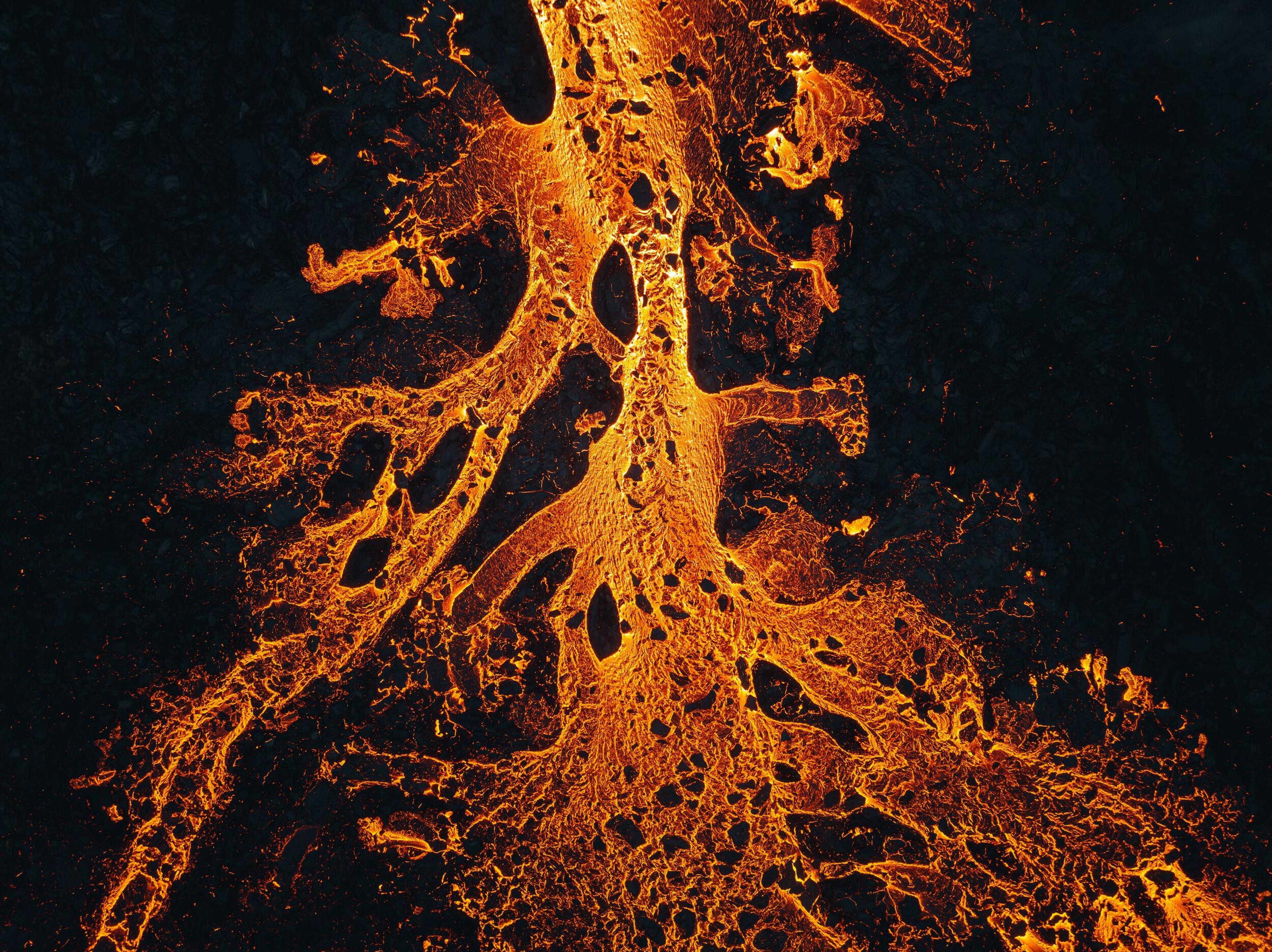 Close-up of molten lava streams with intricate patterns, glowing in vibrant orange against the dark.