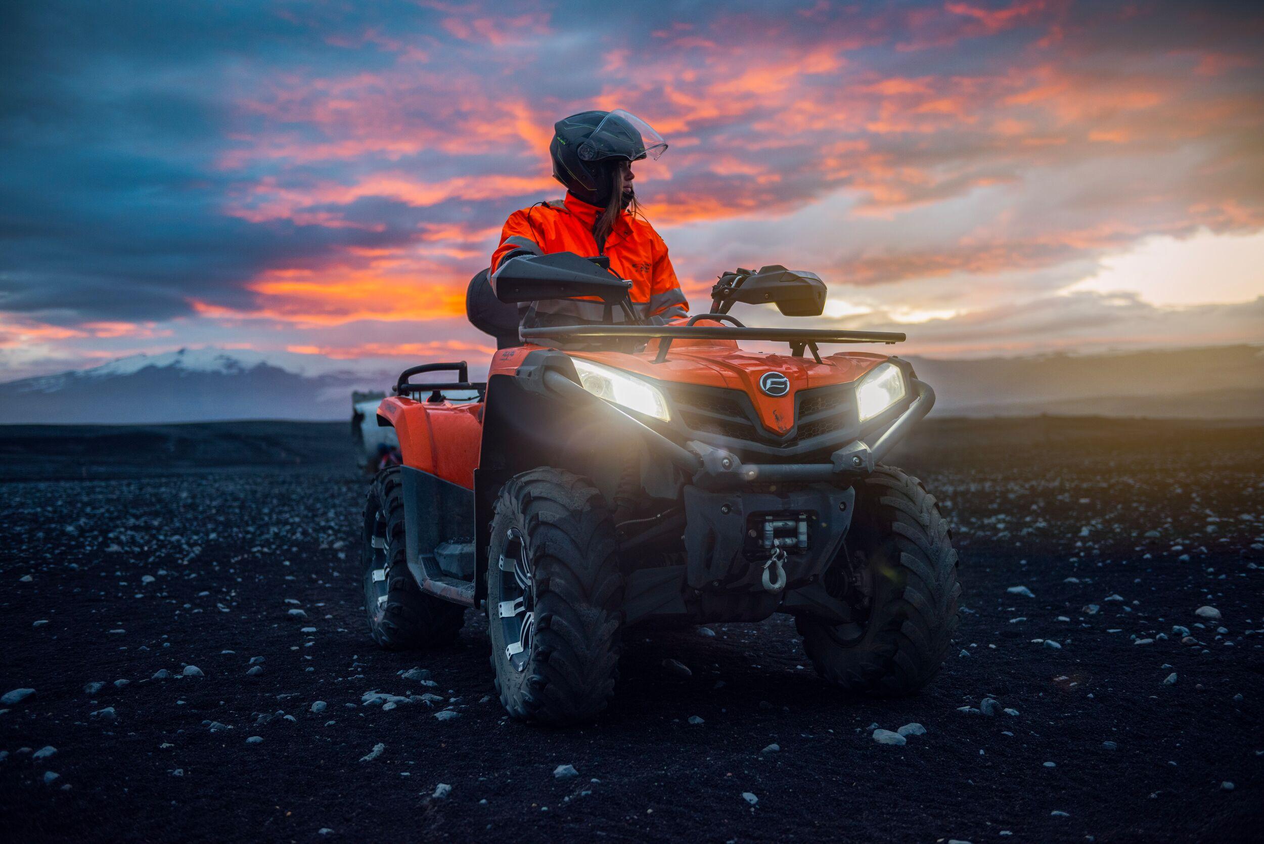 a man is riding an atv in the desert at sunset .