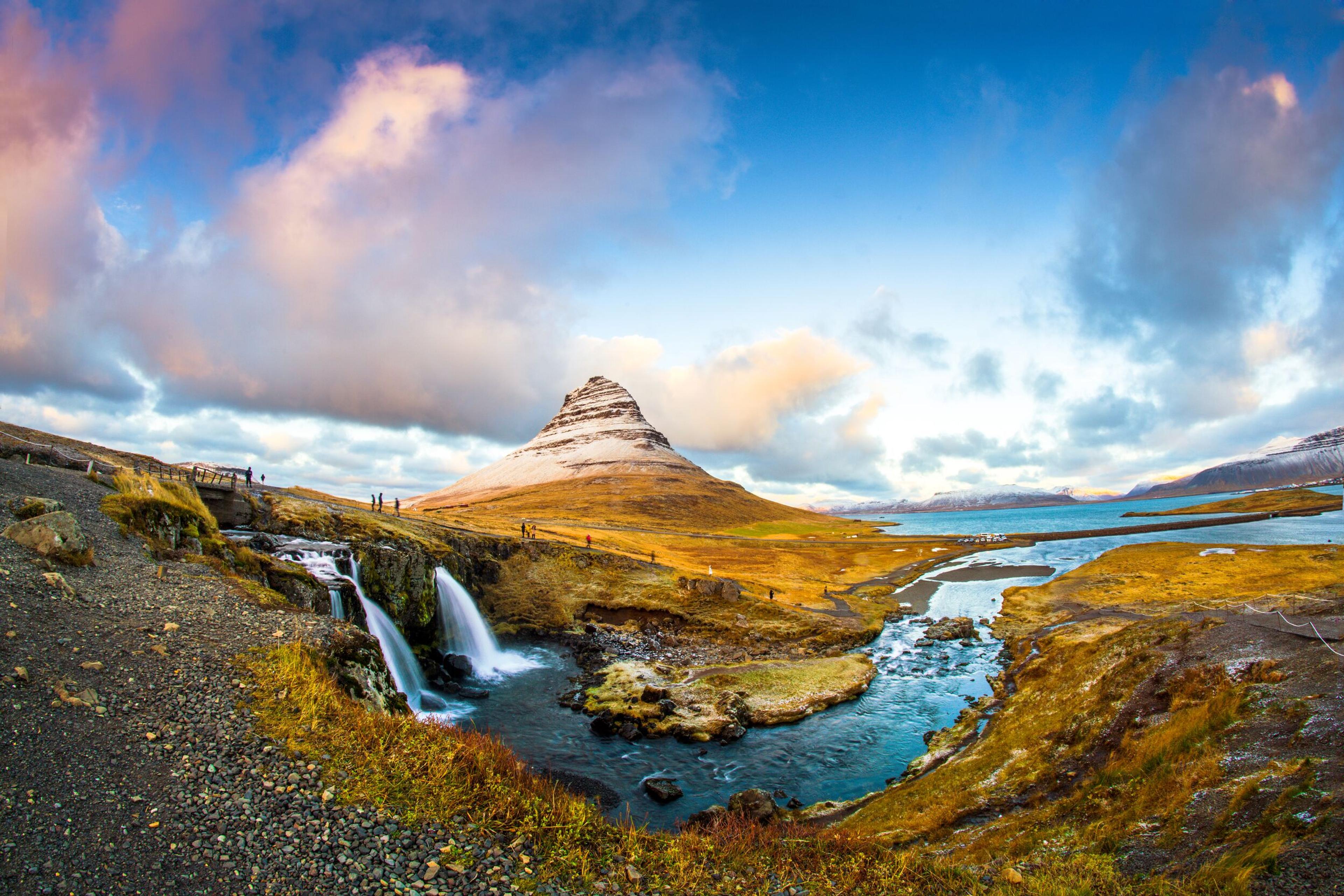 Kirkjufell, the iconic mountain of the Snæfellsnes peninsula, adorned with a delicate blanket of snow contrasting with the surrounding yellow-brown grass