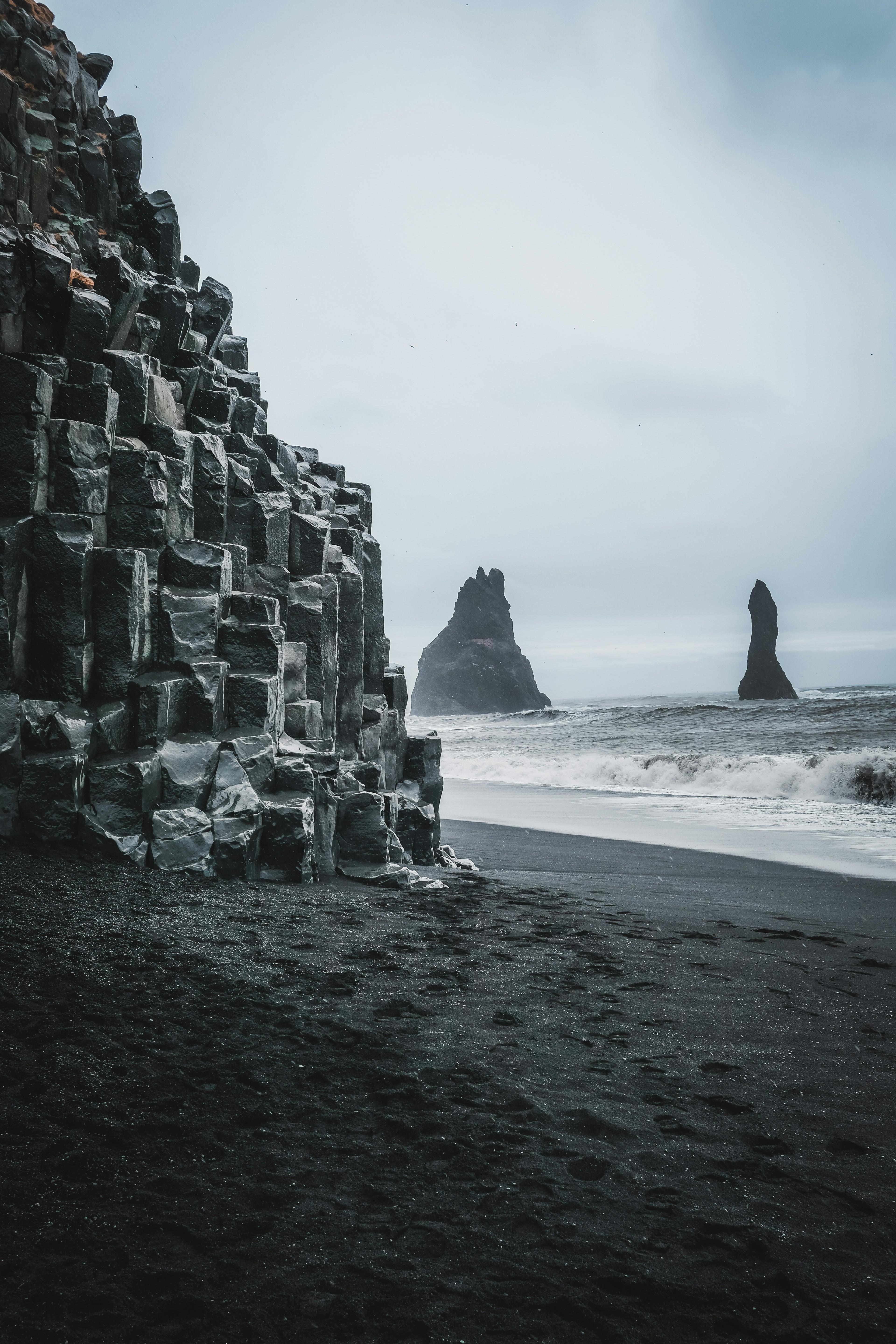 Basalt columns at Reynisfjara black sand beach with the Reynisdrangar sea stacks in the background.