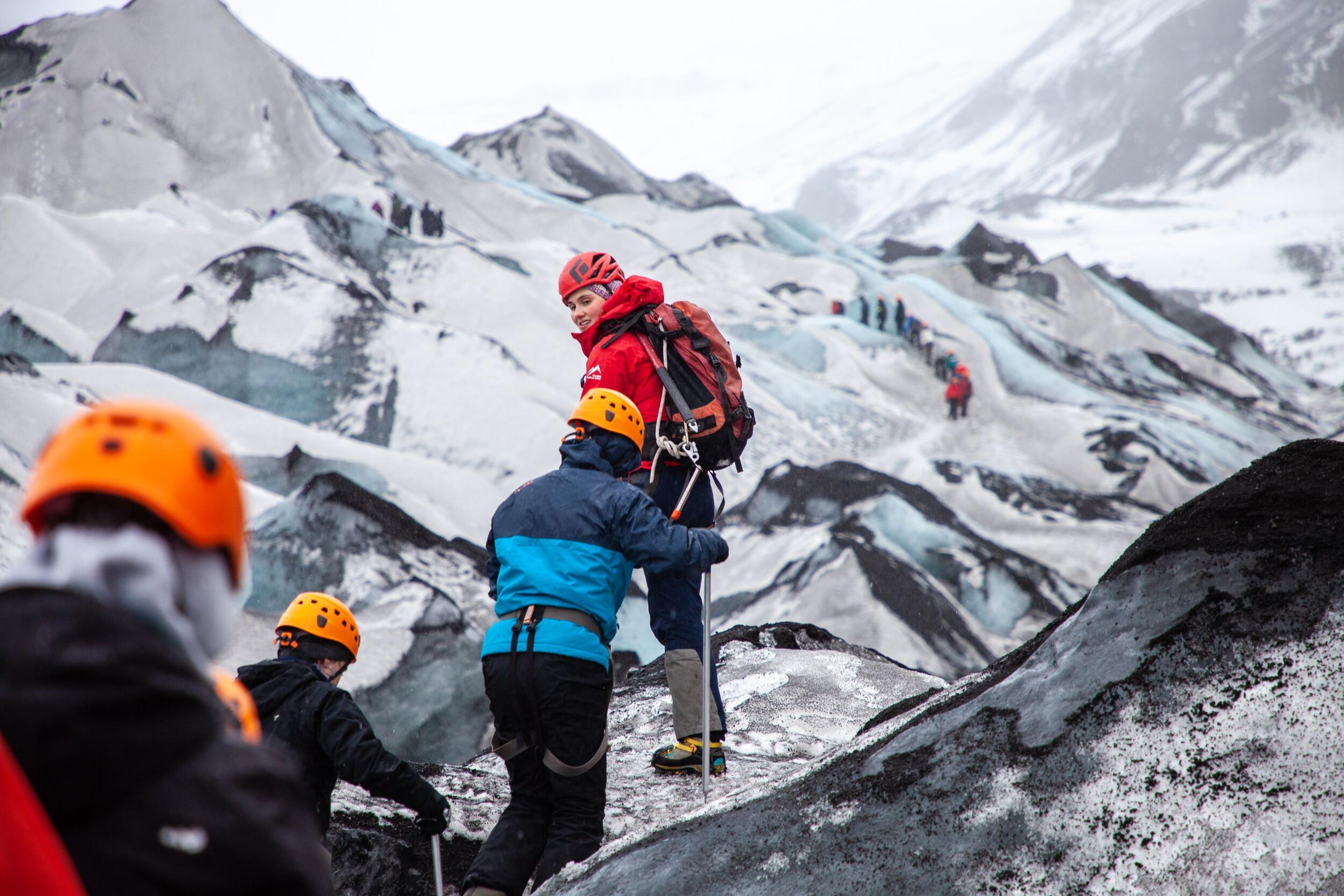 Experience guide leading a group of hikers on top of Sólheimajökull glacier in the south coast of Iceland.