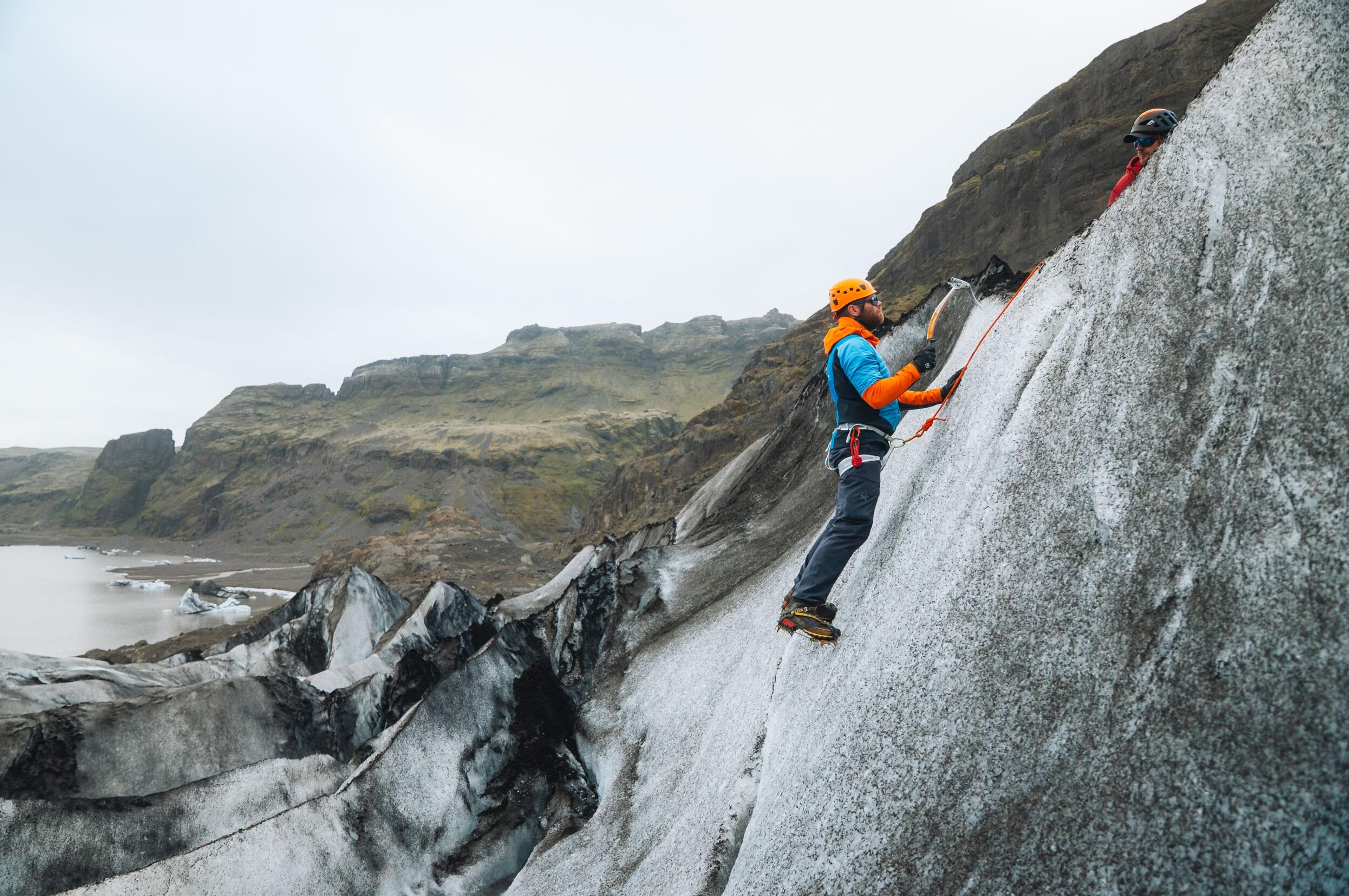 a man is climbing up the side of a mountain .