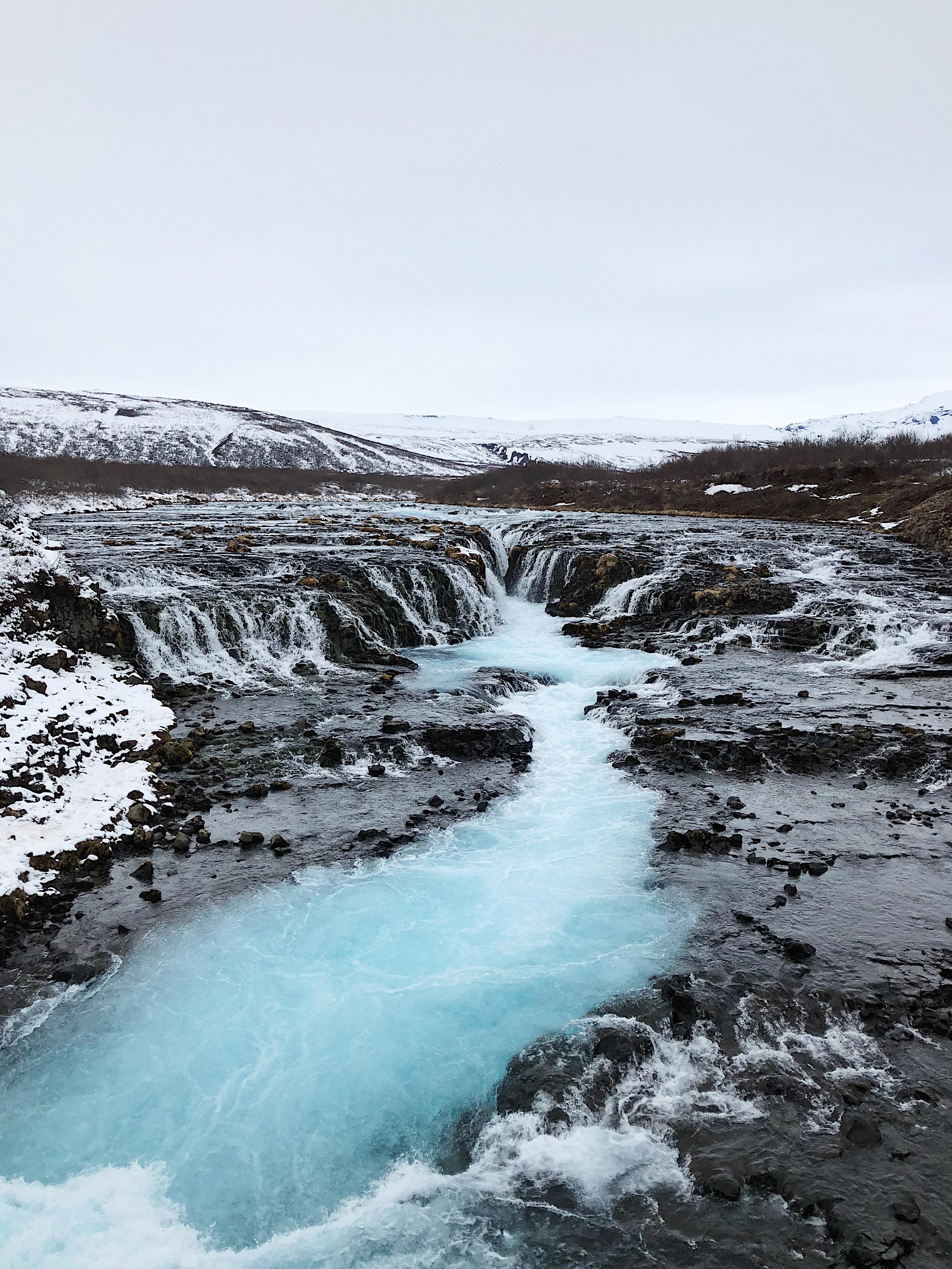 A series of small cascades flowing into a blue river in a landscape