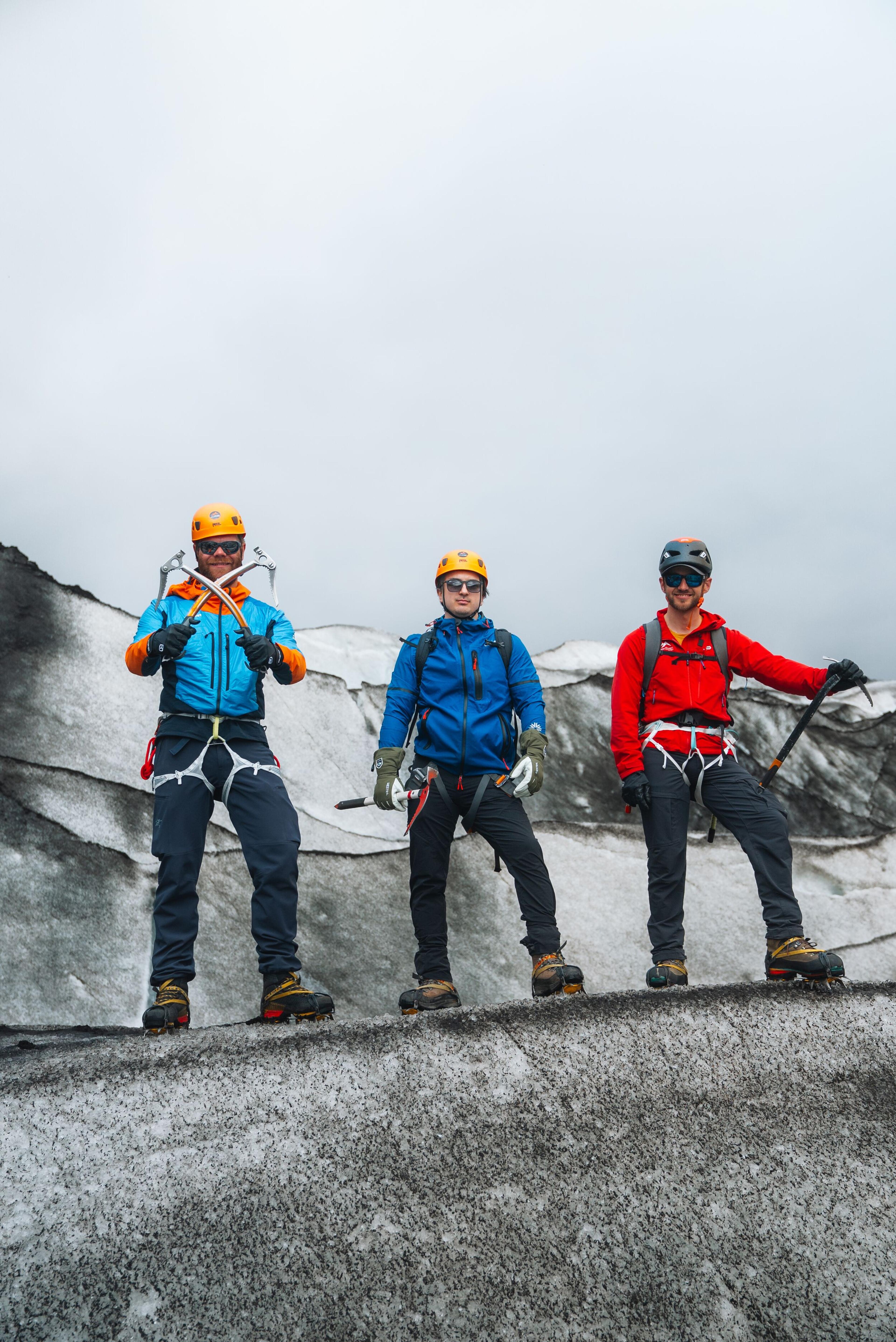 three men are standing on top of a snow covered mountain .