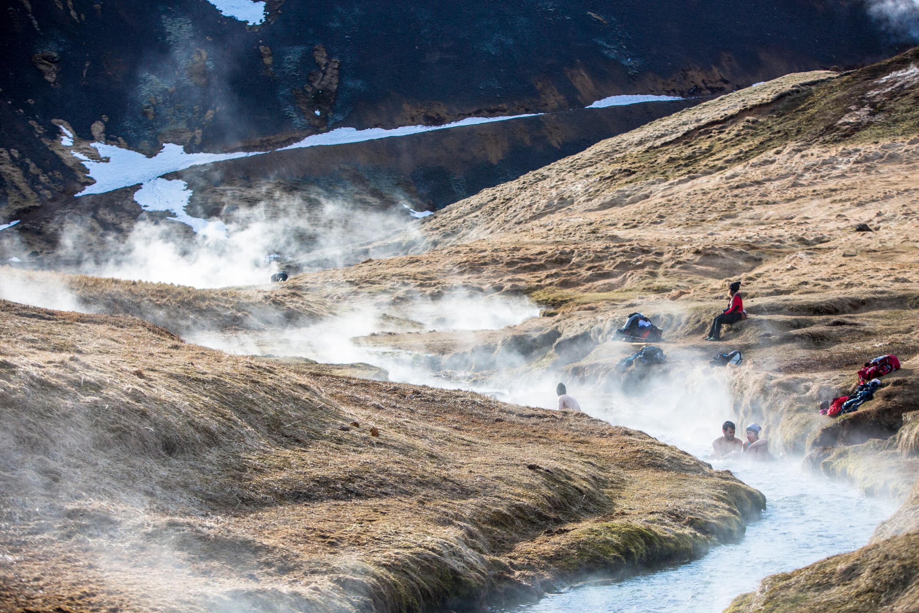 People relaxing in the hot river of Hveradalur, Iceland.