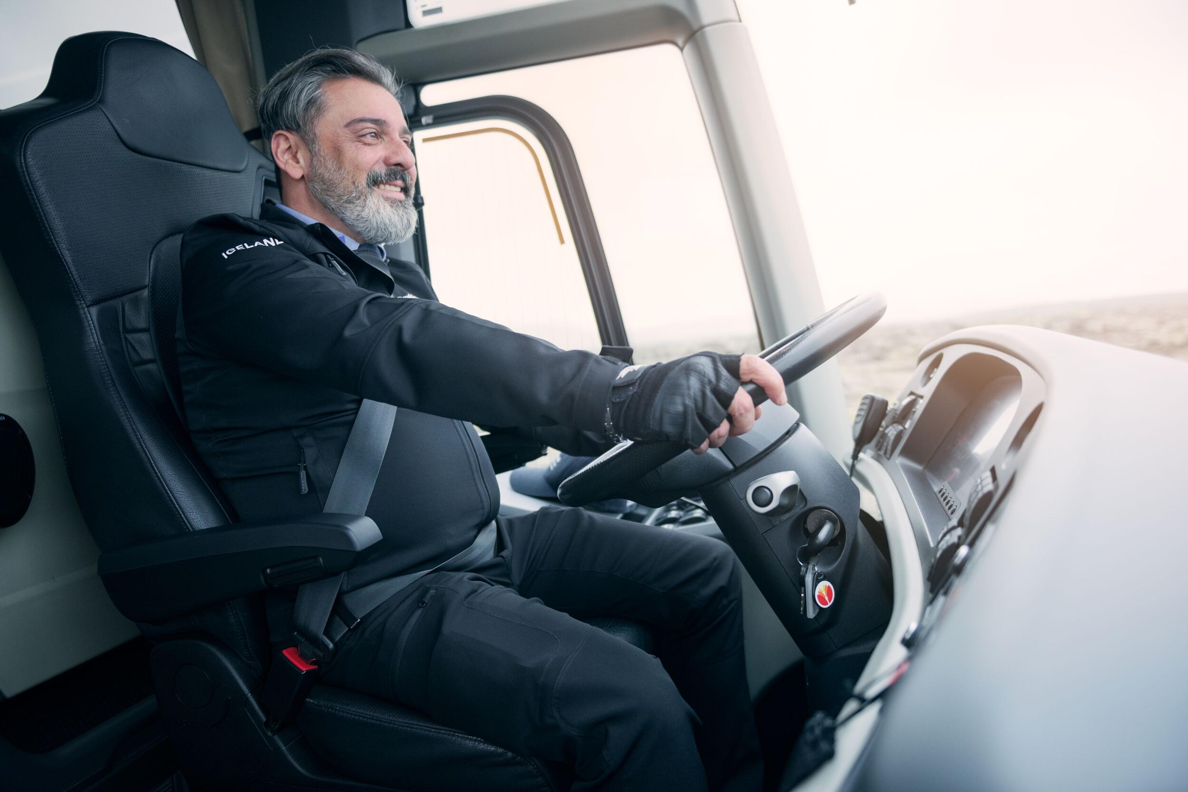 A professional bus driver in uniform driving a coach, showcasing focus and safety while on the road.