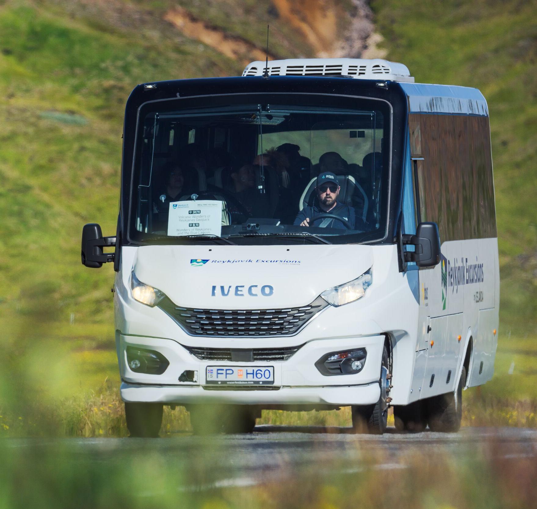 A tour bus driving through a scenic landscape in Iceland.