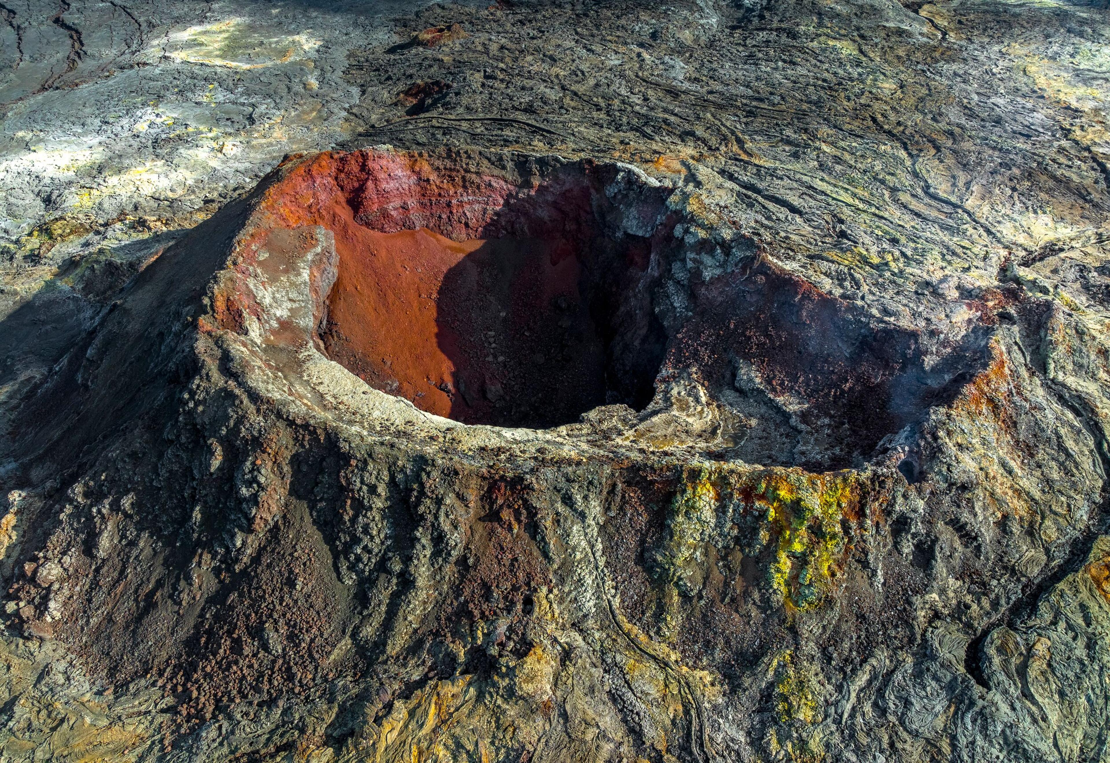 Close-up of a volcanic crater at Fagradalsfjall, Iceland, with rugged, multicolored rock formations surrounding the deep cavity.